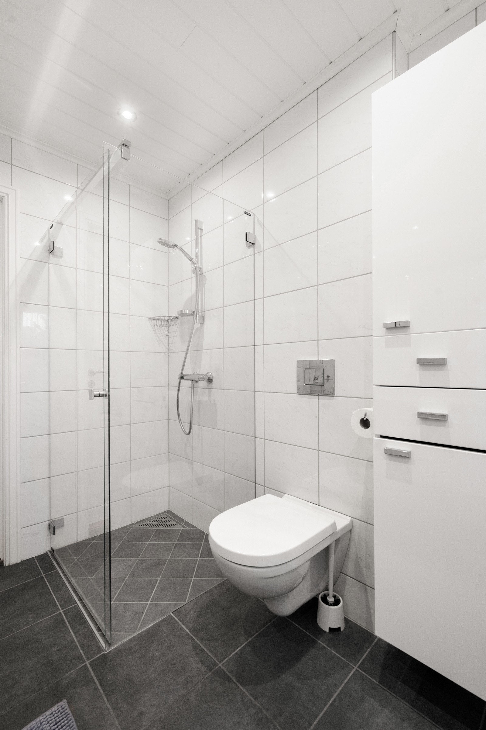 Dusj med innfellbare glassdører og vegghengt toalett. Galleribilde