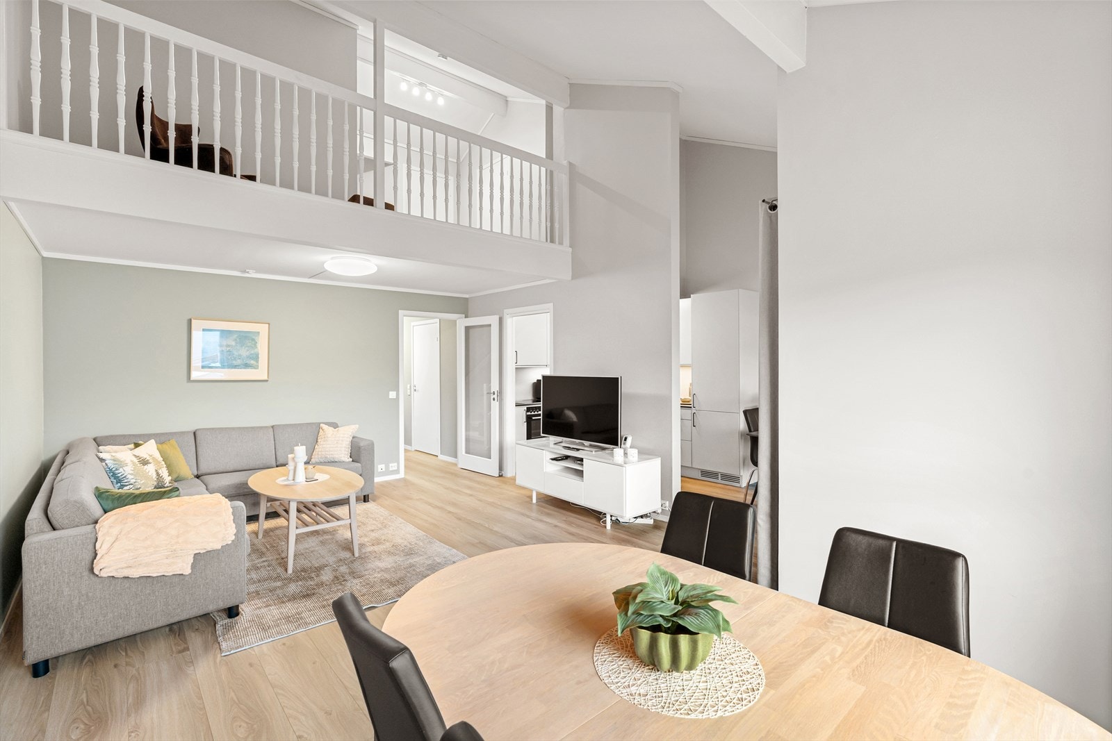 En åpen og luftig stue med naturlige soner og et tilbaketrukket kjøkken. Galleribilde