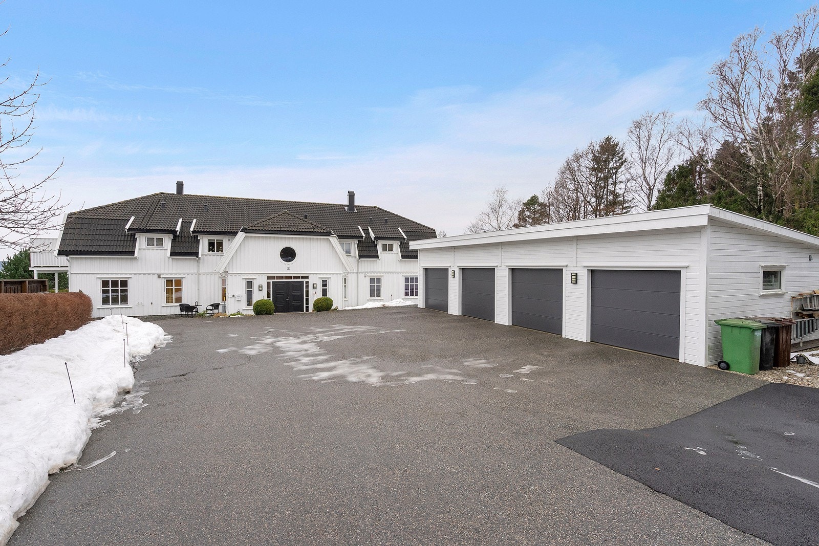 Romslig innkjørsel med garasje i rekke. Sameiet har også gjesteparkering på venstre side av bygget. Galleribilde