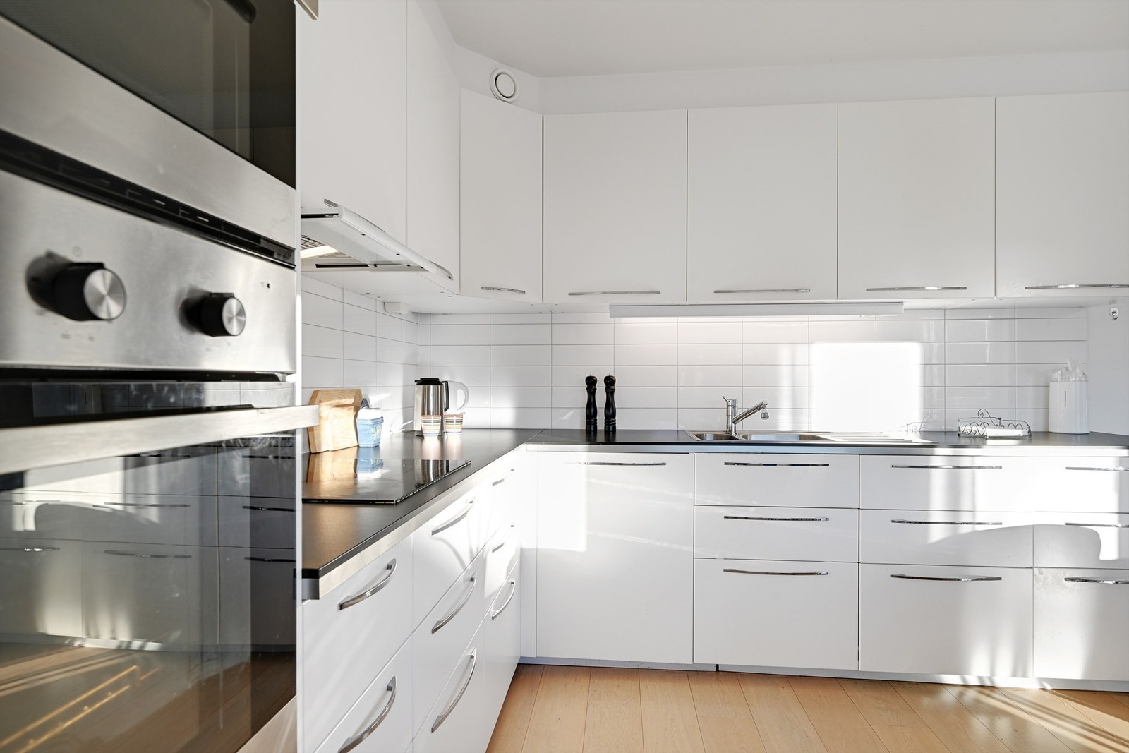 Kjøkkenet har innredning med glatte fronter. Benkeplaten er av laminat. Det er kjøl/fryseskap, oppvaskmaskin, induksjonstopp, mikrobølgeovn og stekeovn integrert i innredningen. Galleribilde