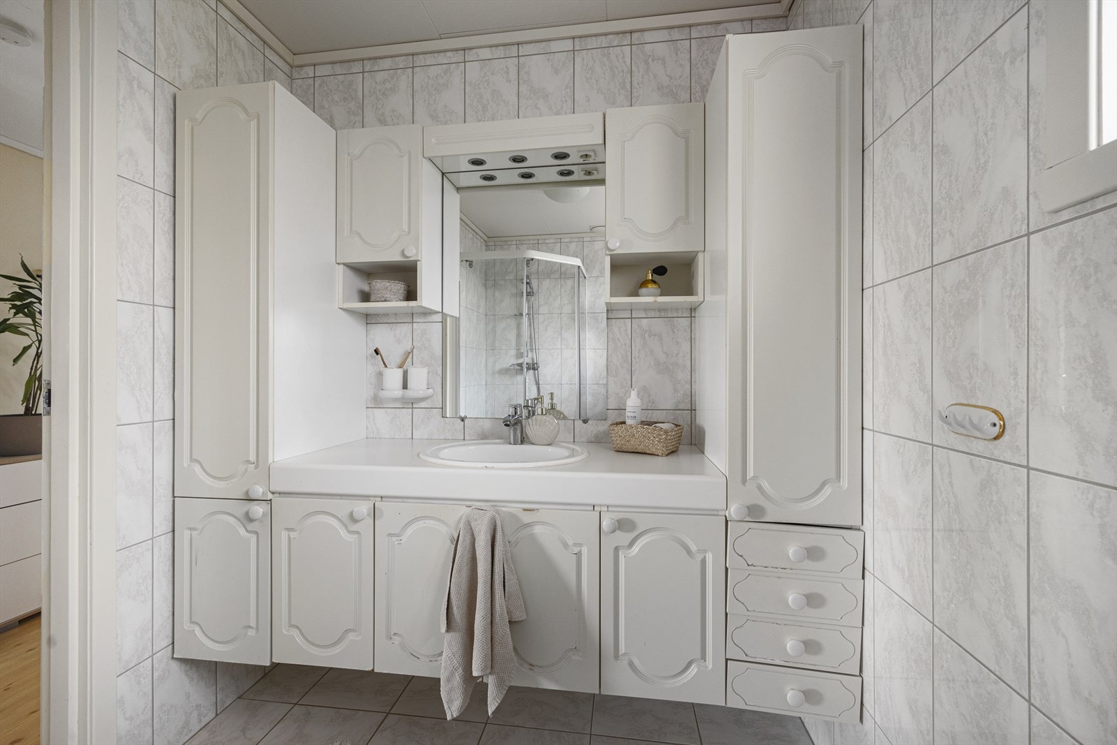 Badet i hovedetasjen er flislagt og utstyrt med servant nedfelt i benkeskap, veggskap, dusjhjørne og toalett. Galleribilde