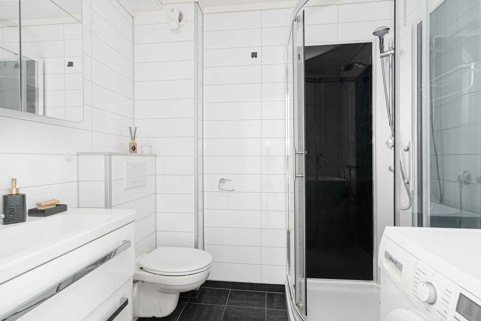 Lyst og pent bad, pusset opp i 2014. Her er det flislagt gulv med varmekabler, veggmontert toalett, dusjkabinett og fin servantinnredning, samt opplegg for vaskemaskin. Galleribilde