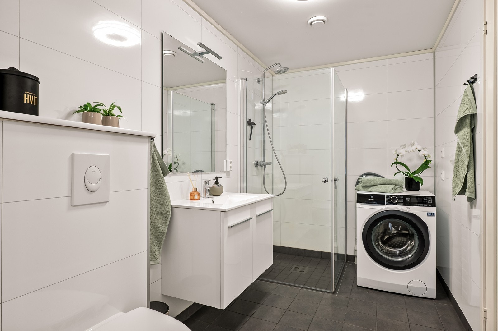 Helfliset bad med dusjhjørne, servantinnredning og opplegg for vaskemaskin. Galleribilde