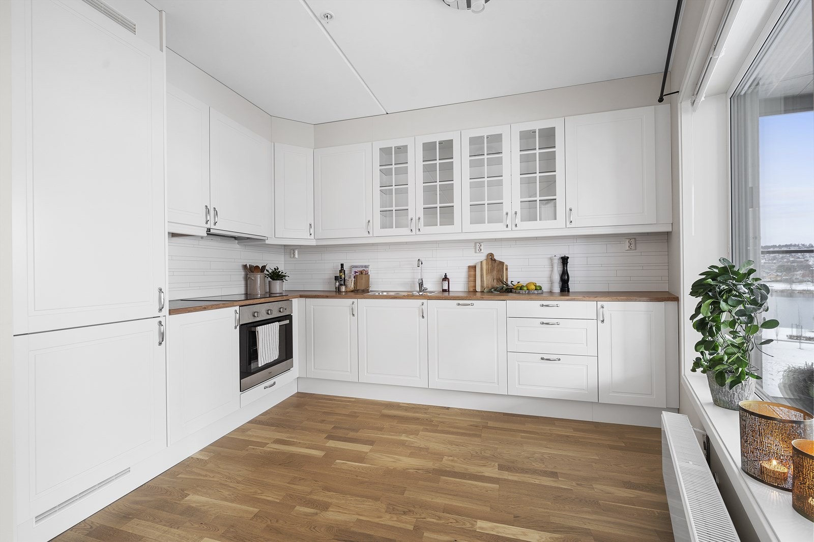 Tidløs, stilren og takhøy kjøkkeninnredning med hvite profilerte fronter og laminert benkeplate. Galleribilde