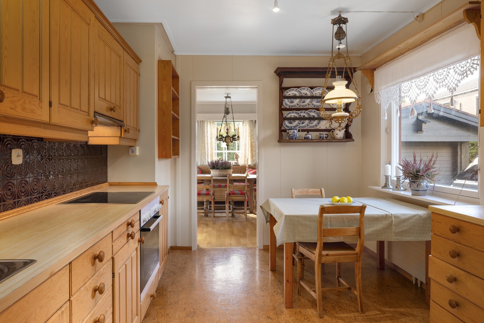 Kjøkkenet har godt med skap- og benkeplass i innredning med laminerte skrog og profilerte fronter. Noen overskap med glass. Laminert benkeplate med kjøkkenkum og med fliser og belysning over benkeplaten Galleribilde