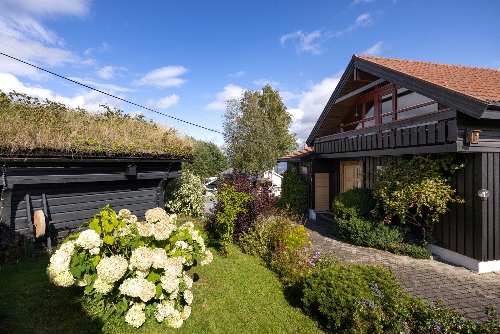 Tomten er pent opparbeidet med plen, hekker og beplantninger Galleribilde