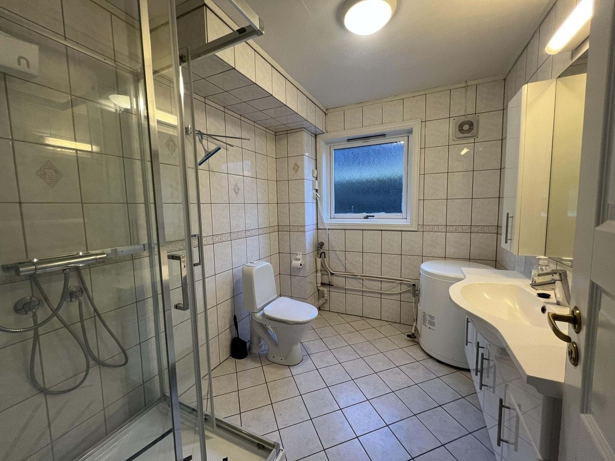 Helfliset bad med dusjkabinett og opplegg for vaskemaskin. Galleribilde