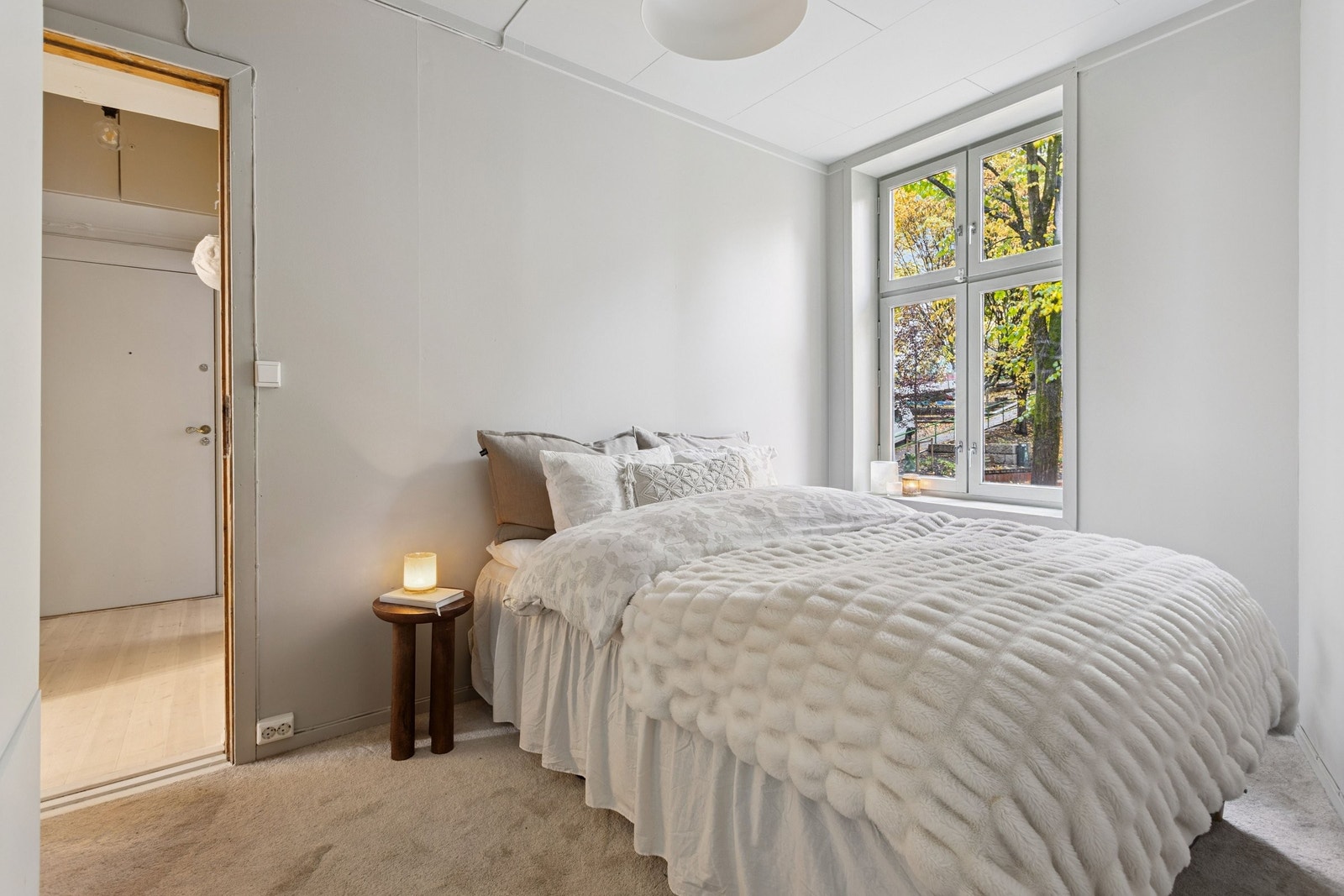 Hovedsoverom med nydelige trær som nærmeste nabo. God plass til nattbord på hver side av sengen. Galleribilde