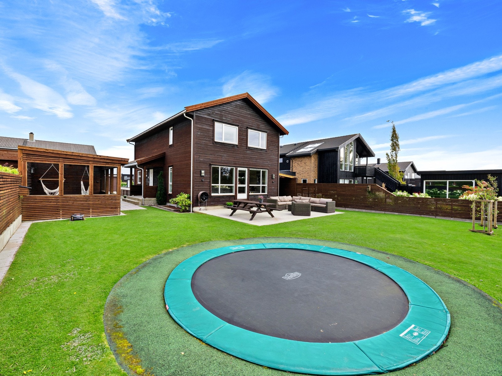 Hagen er funksjonelt og pent opparbeidet med markterrasse i betong, klippekant rundt plenen og nedfelt trampoline. Galleribilde