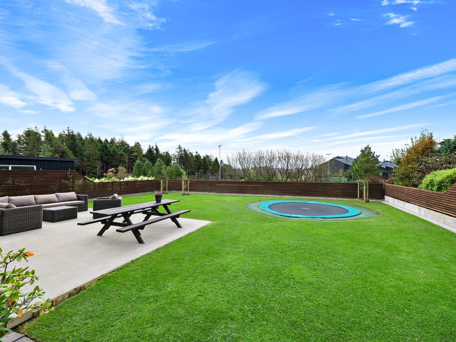Markterrasse i betong, klippekant rundt plenen og nedfelt trampoline. Galleribilde