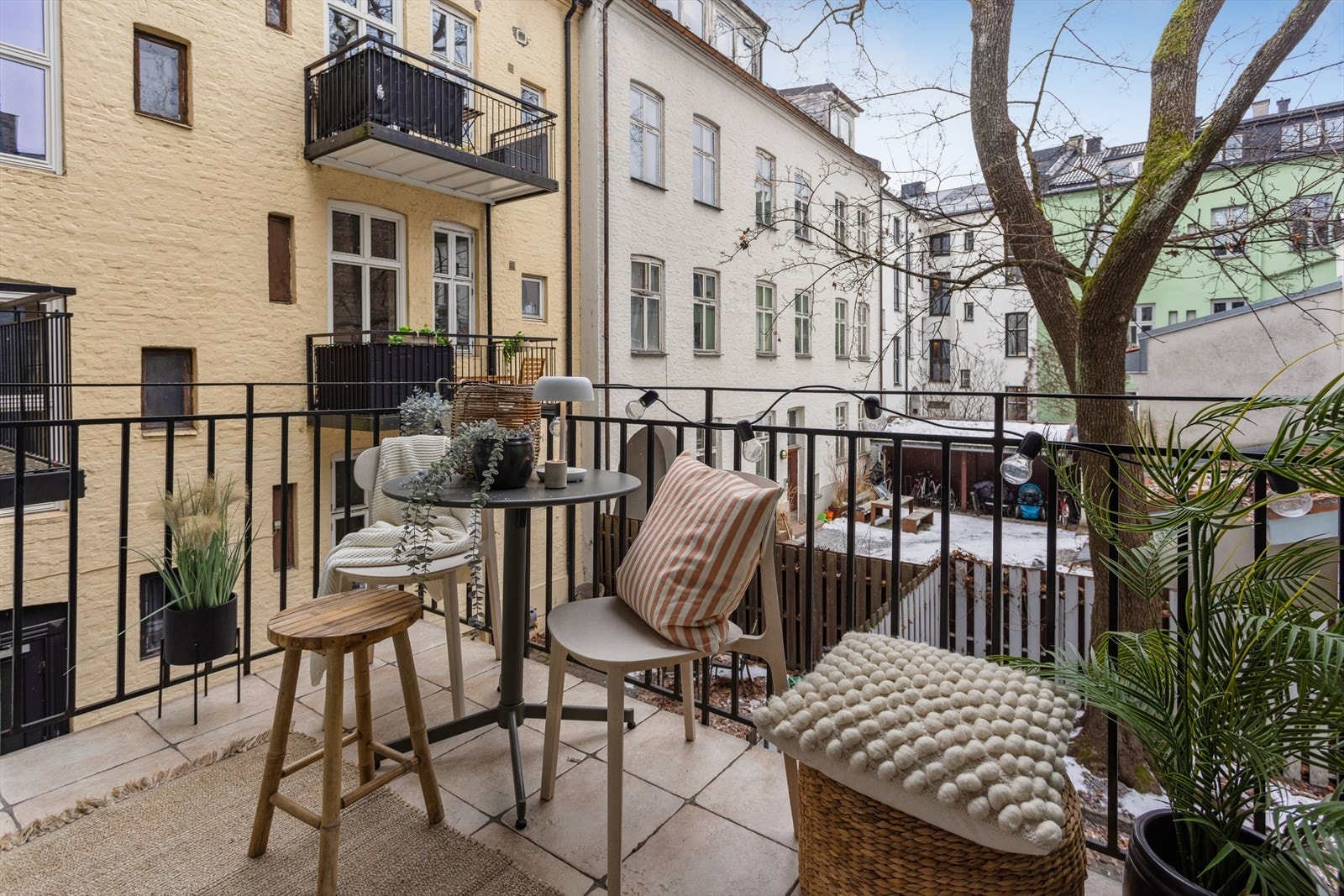 Fra balkongen er det utsikt mot et rolig bakgårdsmiljø, med flislagt gulv som gir et solid underlag. Galleribilde