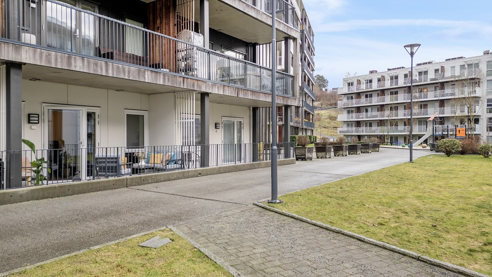 Trivelige fellesområder med gressplen og lekeplass i sameiet Galleribilde