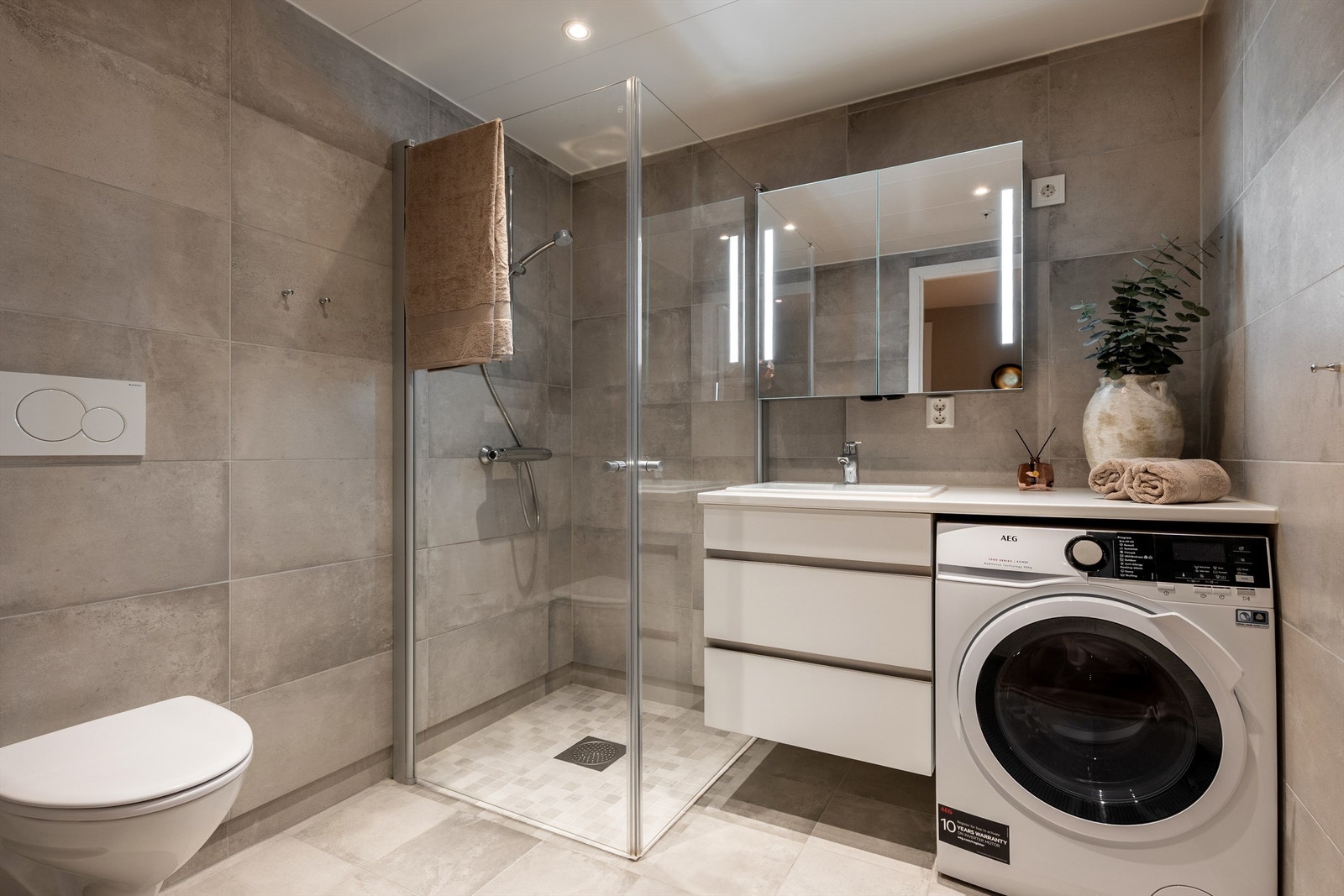 Badet er innredet smart; vaskemaskinen har plass under servantbenken som kan benyttes til eksempelvis bretting av tøy. Galleribilde