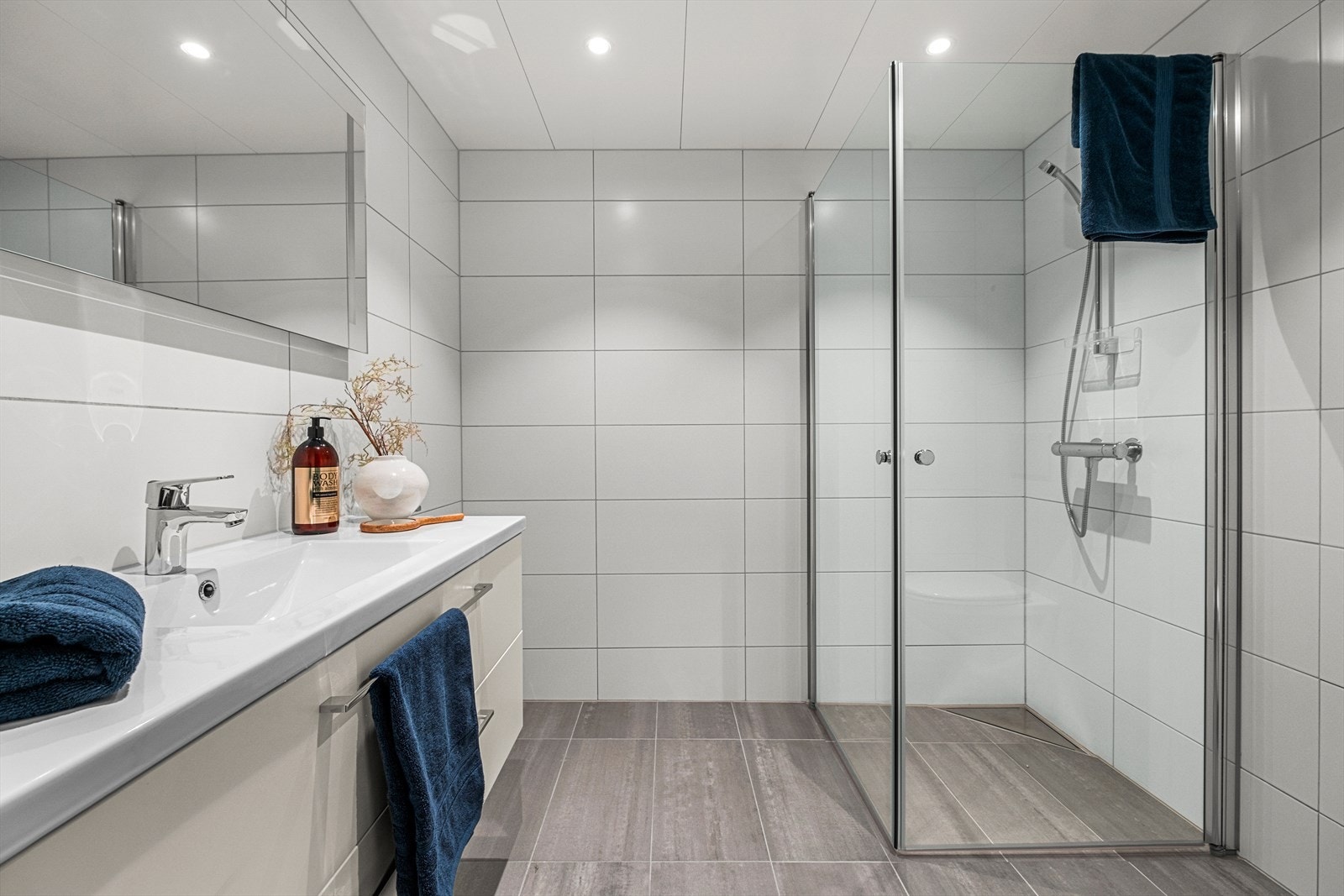 Pent flislagt baderom på 4,5 kvm. Her får du flott servant med underskap, dusjhjørne, vegghengt WC og opplegg for vaskemaskin Galleribilde