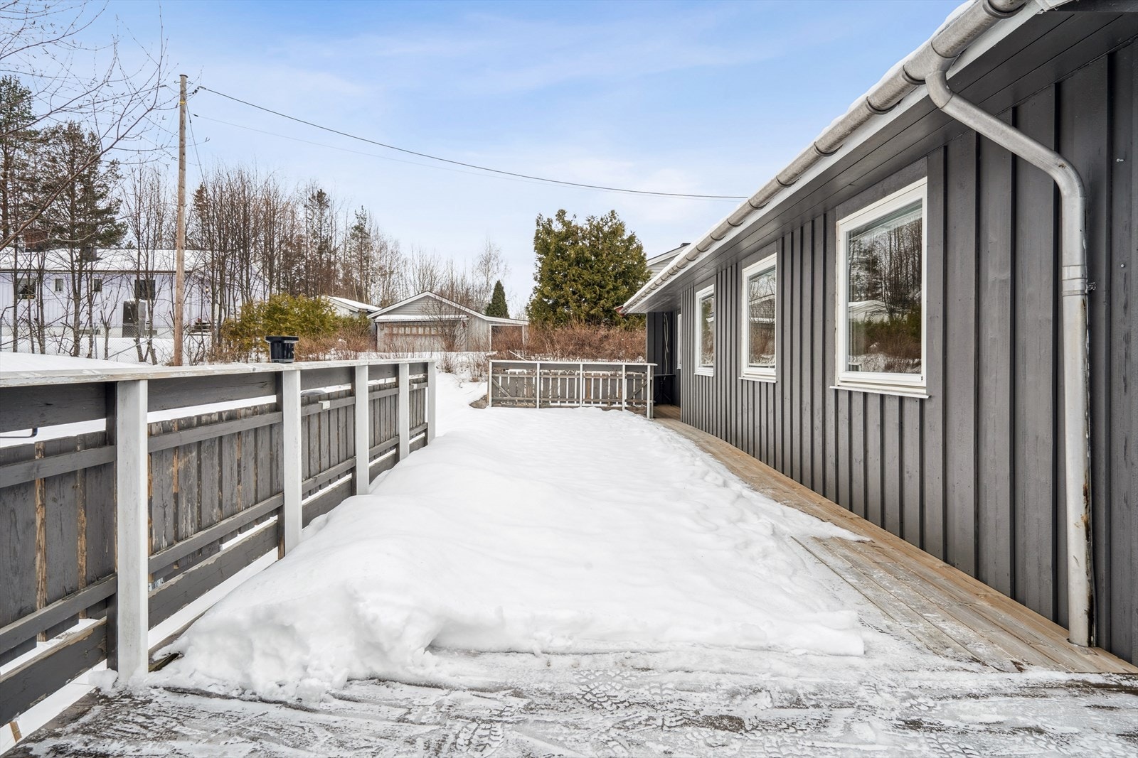 En langstrakt terrasse strekker seg langs store deler av boligens fasade. Galleribilde