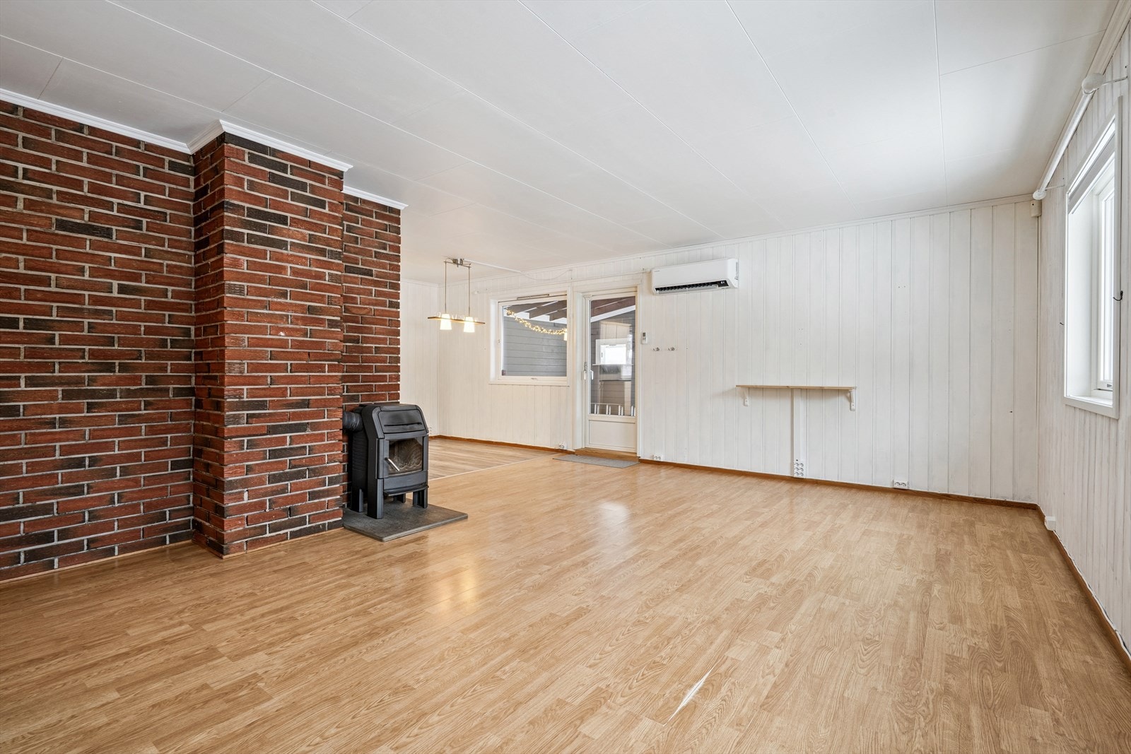 Vinkelformet stue med både vedovn og nyere varmepumpe. Galleribilde