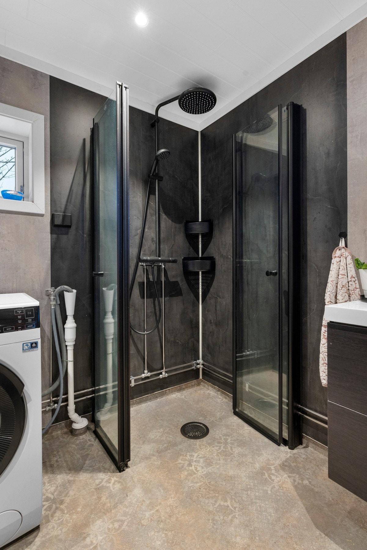 Innredningen består av servant med glatte fronter, veggskap med speil, opplegg for vaskemaskin, klosett og dusjhjørne Galleribilde