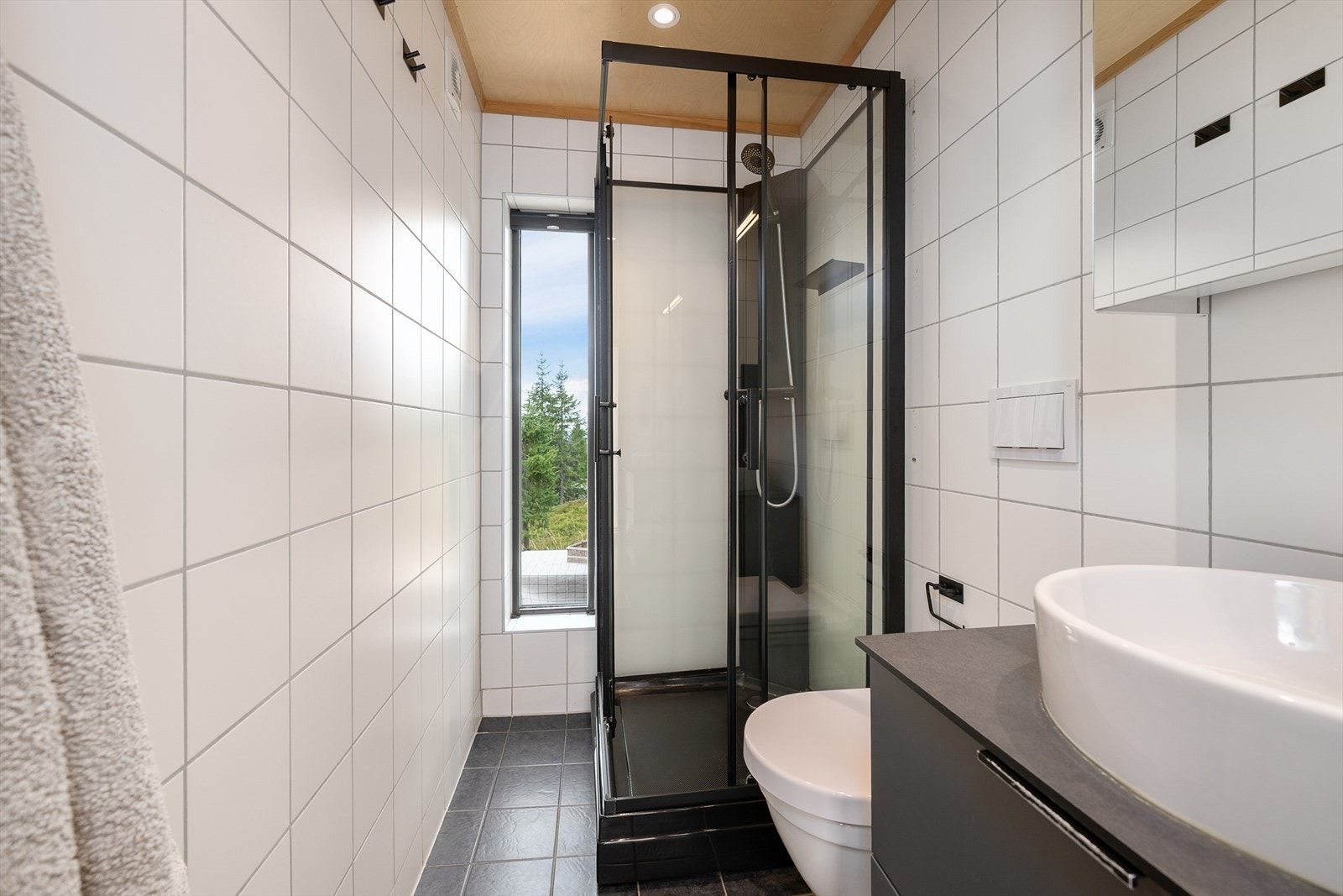 Stilrent, flislagt bad med dusjhjørne og vegghengt toalett. Galleribilde