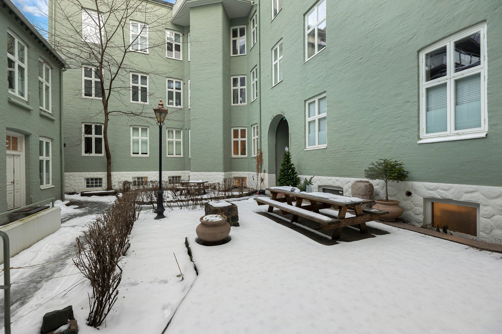 Pent opparbeidet bakgård med terrasseplatting, grillplass og sittegrupper samt noe beplantninger Galleribilde