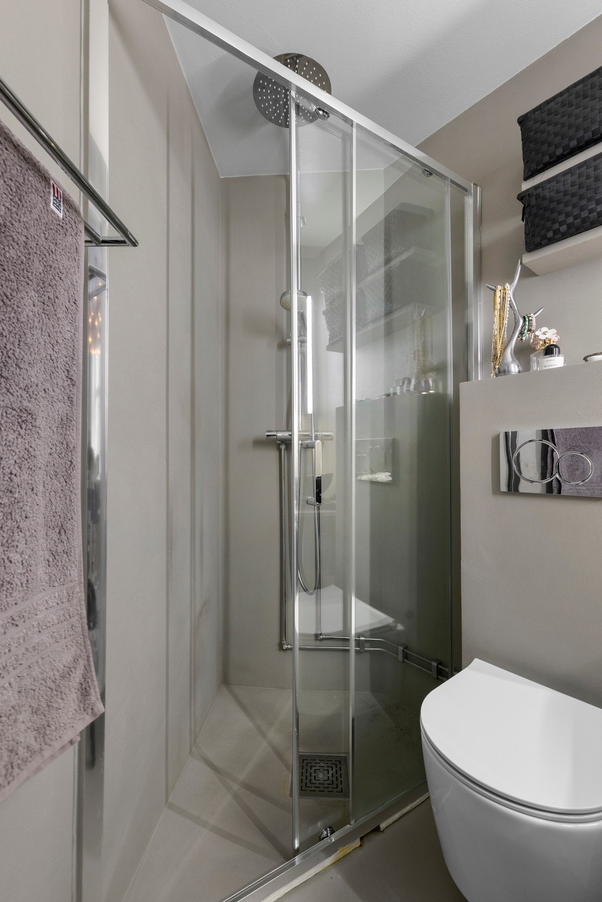 Dusjhjørne med skyvedør og termostatstyrt dusjbatteri i krom med både hånd- og regnfallsdusj. Innebygget sisterne med vegghengt toalett. Galleribilde