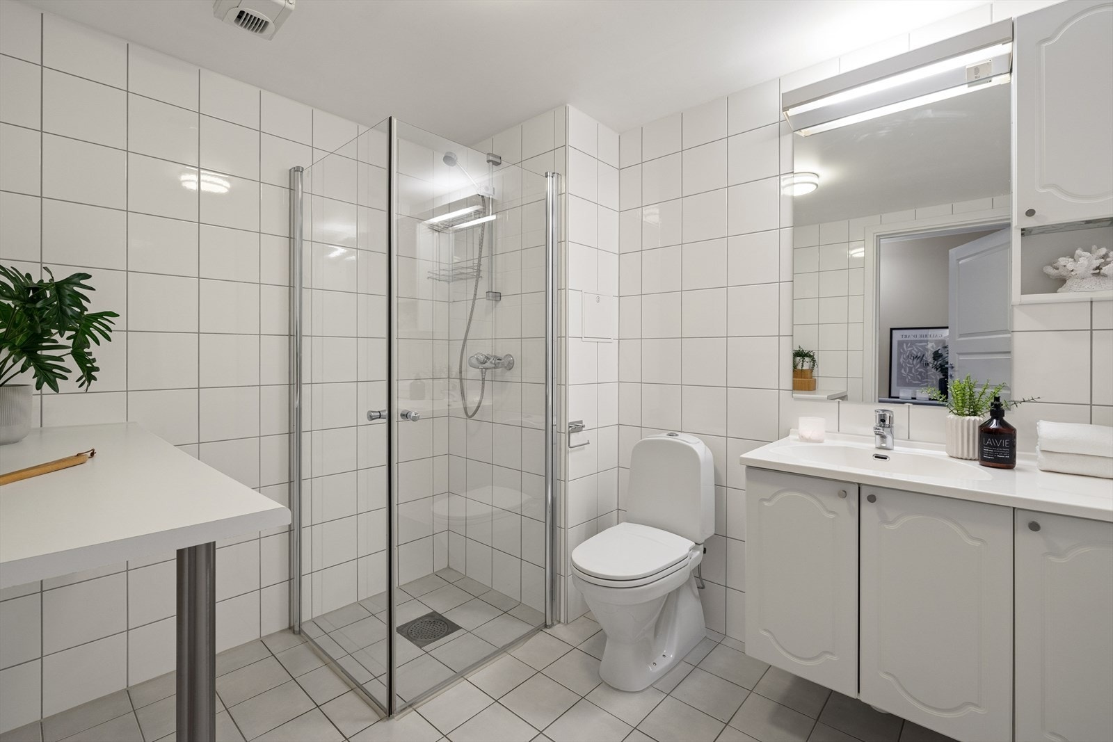 Innredningen består av benkeskap og veggskap med profilerte fronter, servant, gulvstående toalett og en dusjsone med sluk i gulv. For økt komfort er det installert varmekabler i gulvet. Galleribilde