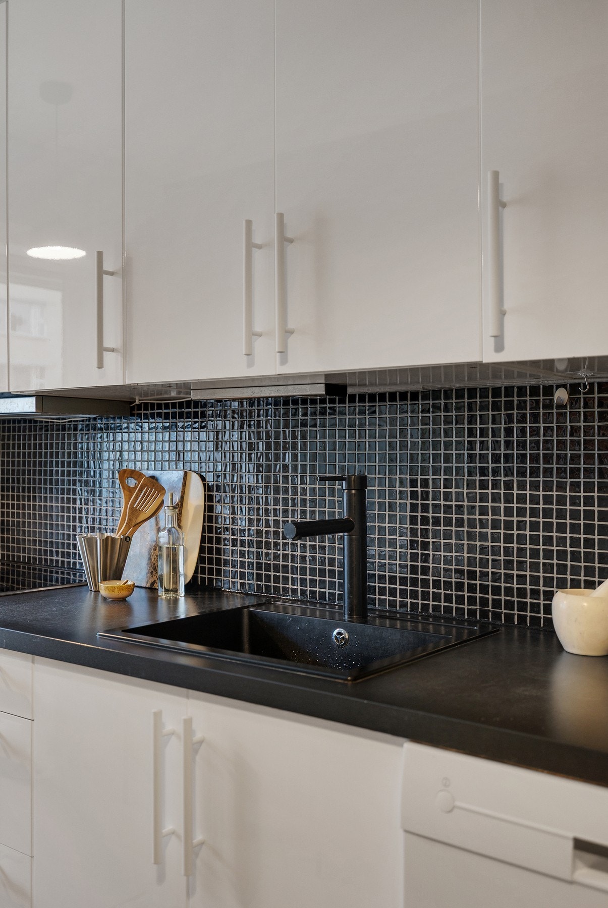 Kjøkkeninnredning med glatte fronter, fliser på vegg over benkeskap og laminat benkeplate med nedfelt kum. Galleribilde