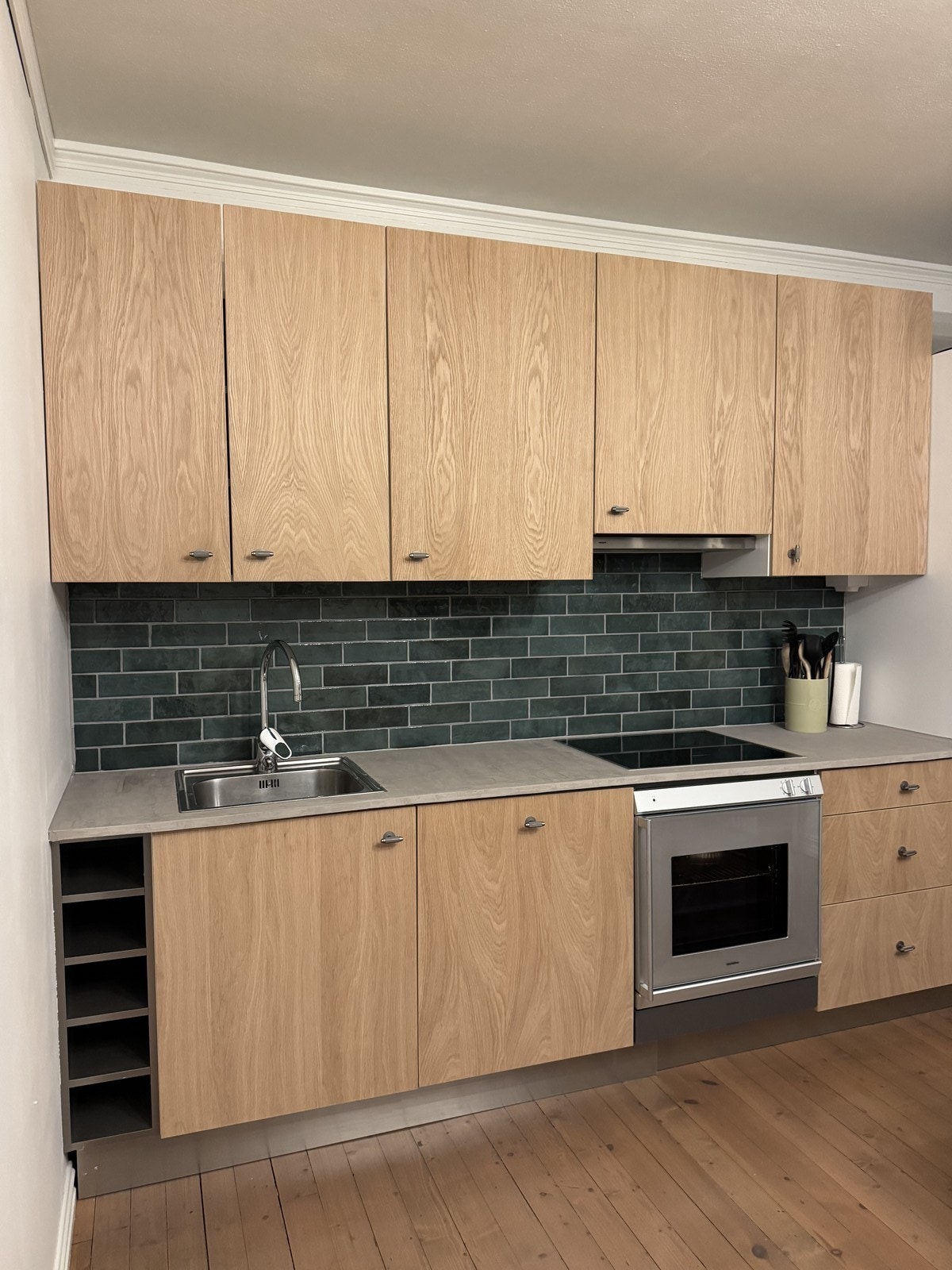 Flott kjøkken med integrerte hvitevarer som oppvaskmaskin, komfyr, kombiskap og platetopp. Galleribilde