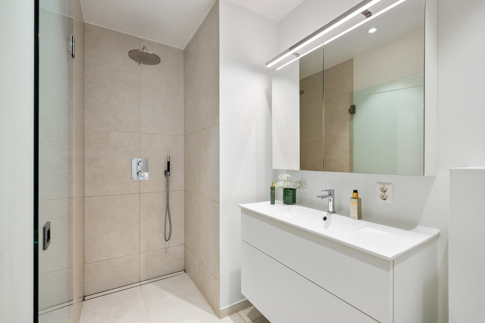 Pent bad med dusjhjørne, vegghengt toalett og servant på underskap. Galleribilde