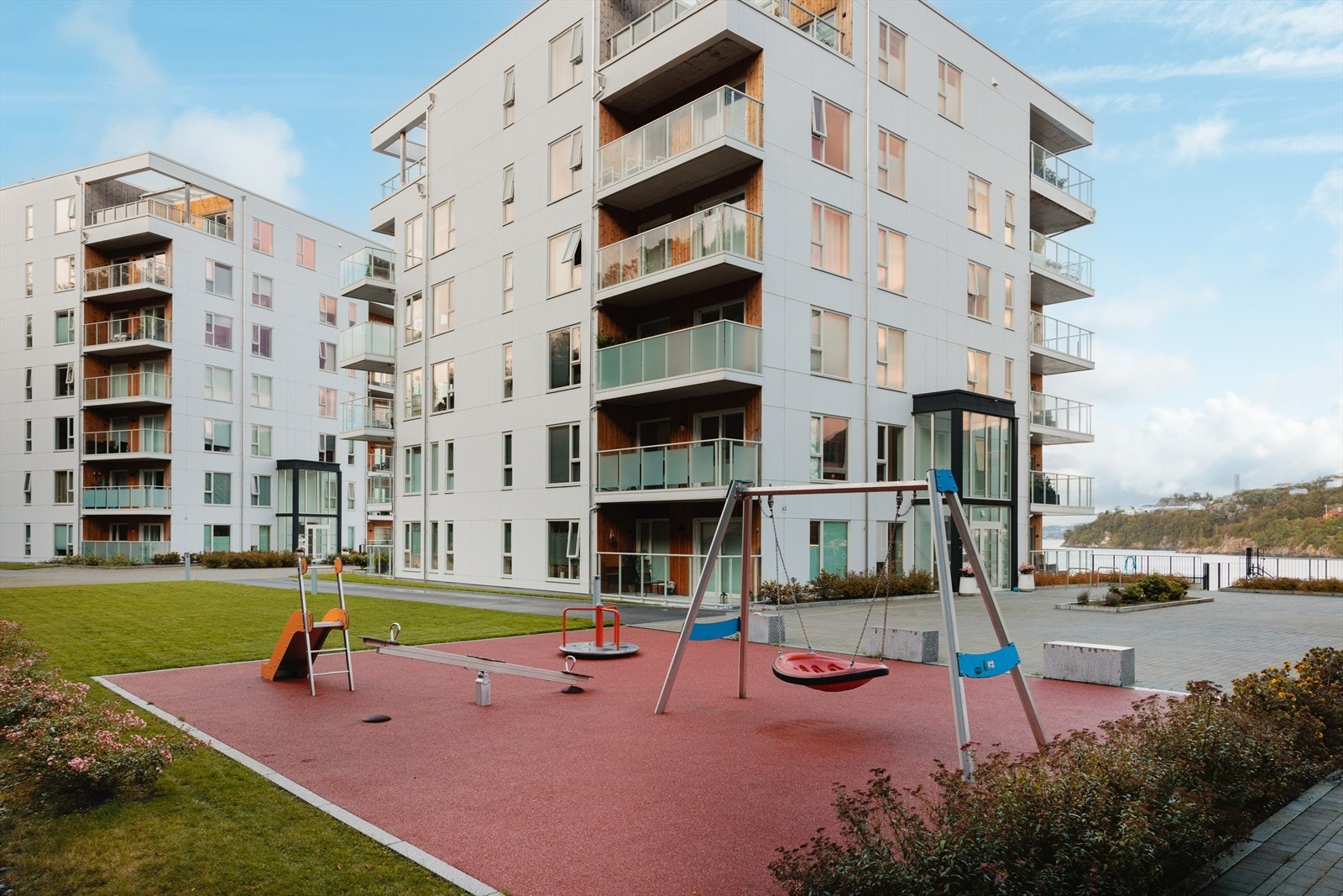 Bilfritt parkanlegg i borettslaget med lekeplass, gressplener og benker. Galleribilde