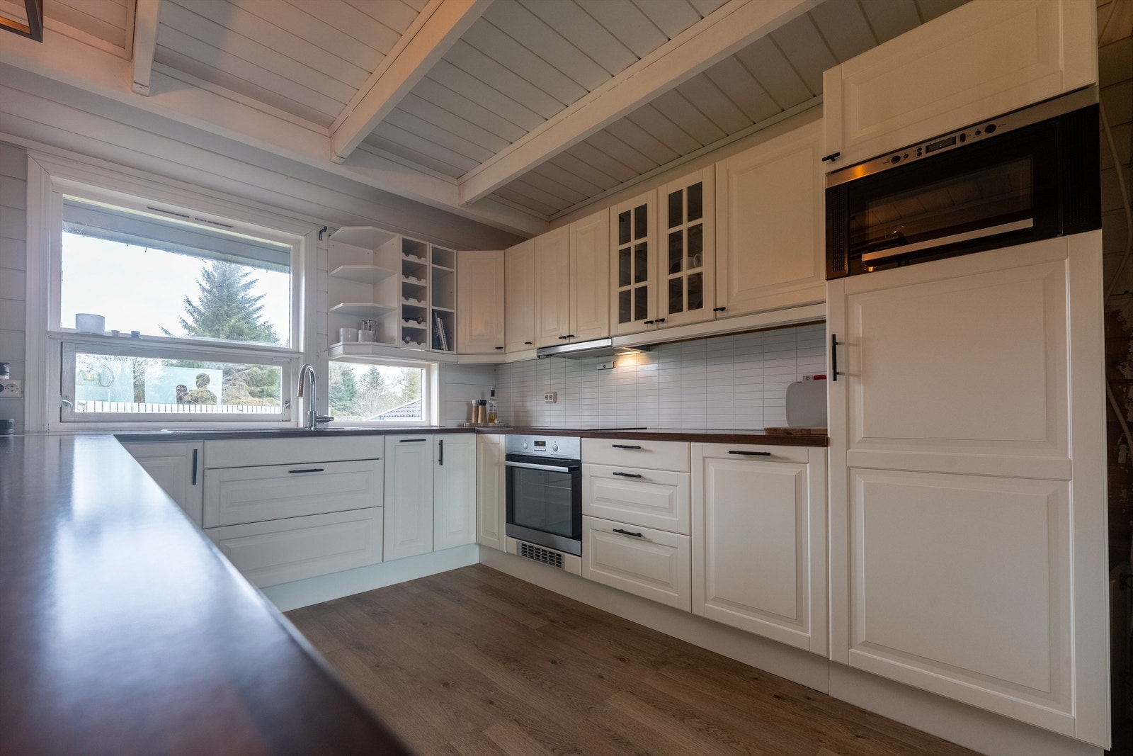 Kjøkkenet ligger tilbaketrukket fra spisestuen, og er pent innredet med lyse slette flater og benkeplate i kontrast. Galleribilde