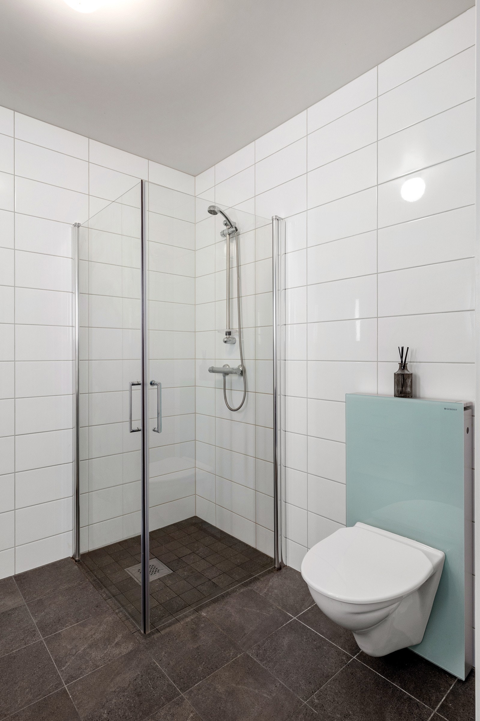 Det er innredet med vegghengt toalett med glassbox sisterne, servant og nedsenket dusjsone. Galleribilde