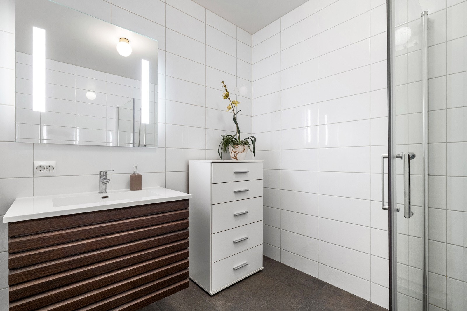 Badet ligger praktisk plassert mellom kjøkken og stue, og er lekkert helfliset med varmekabler. Galleribilde