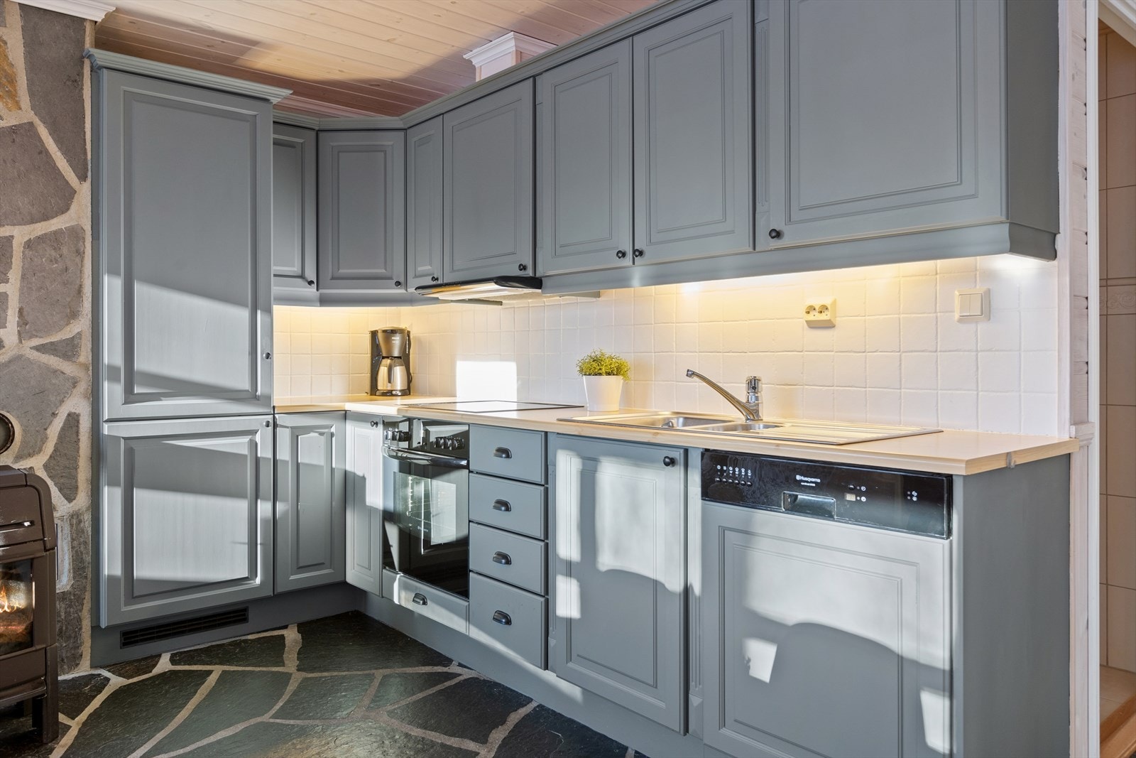 Kjøkkenet er tidløst innredet med grå, profilerte fronter og trefarget benkeplate i laminat. Et godt utnyttet kjøkken hvor man har god lagringsplass i skap og skuffer. Galleribilde