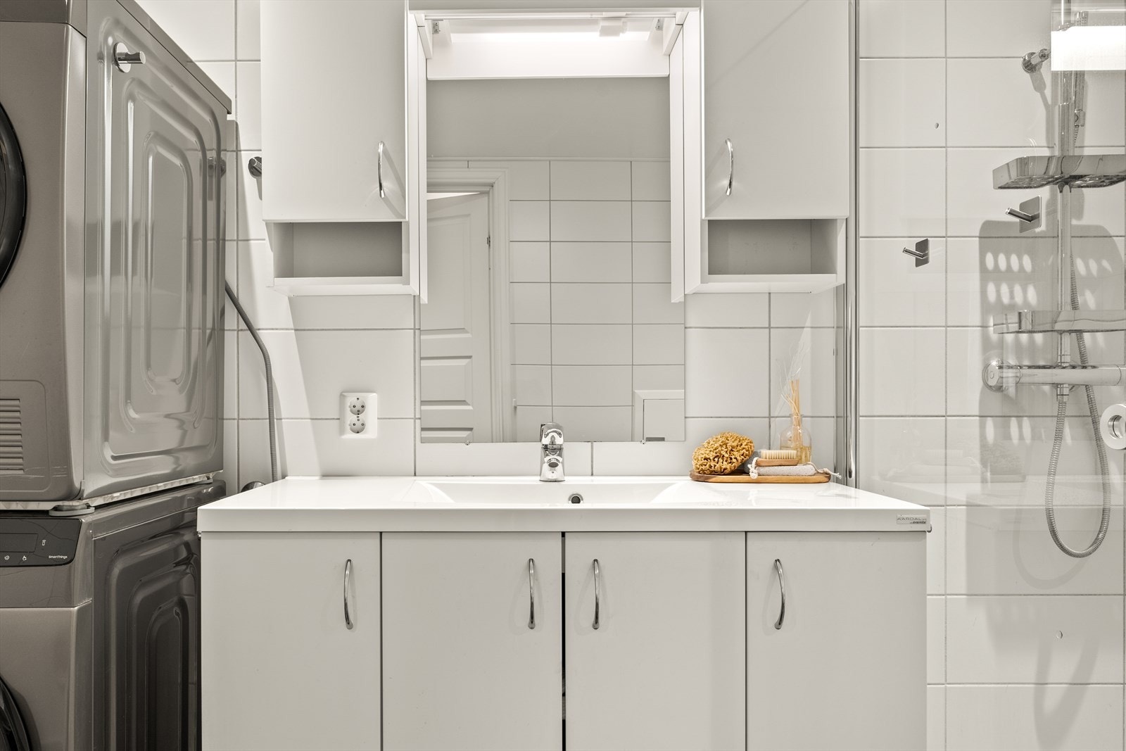 Pent innredet med lyse fliser og varmekabler i gulv. Badet har \nedfelt servant med rom for oppbevaring i underskap, speil med belysning, toalett og dusjhjørne med regndusjarmatur. Galleribilde