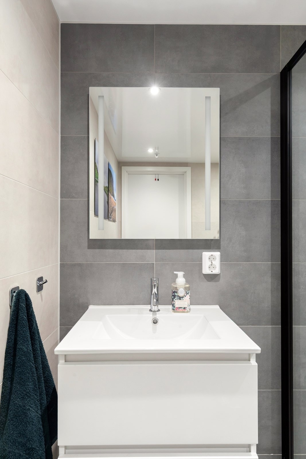 Fargene på badet står godt til det hvite baderomsmøbelet og til de sorte detaljene på dusjdørene. A-konto felles varmtvann er inkludert i fellesu
tgiftene Galleribilde