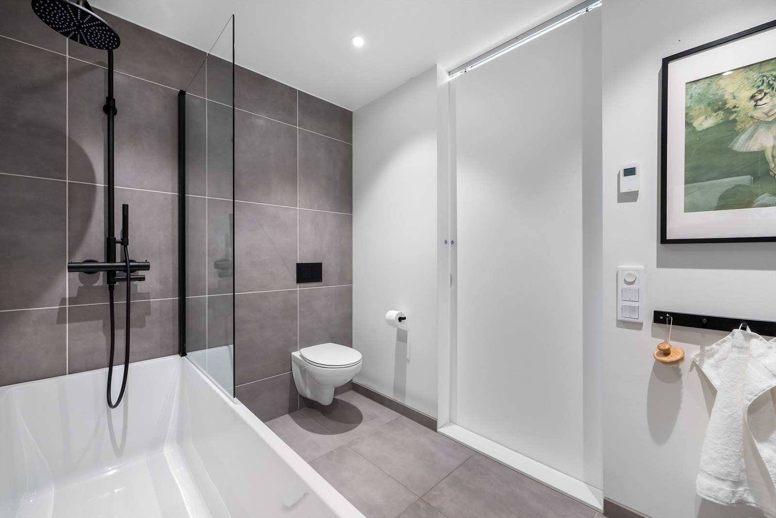 Badet i 2. etasje har hvite vegger, grå fliser og behagelig gulvvarme. En dus grønn fondvegg gir rommet et moderne og harmonisk uttrykk Galleribilde