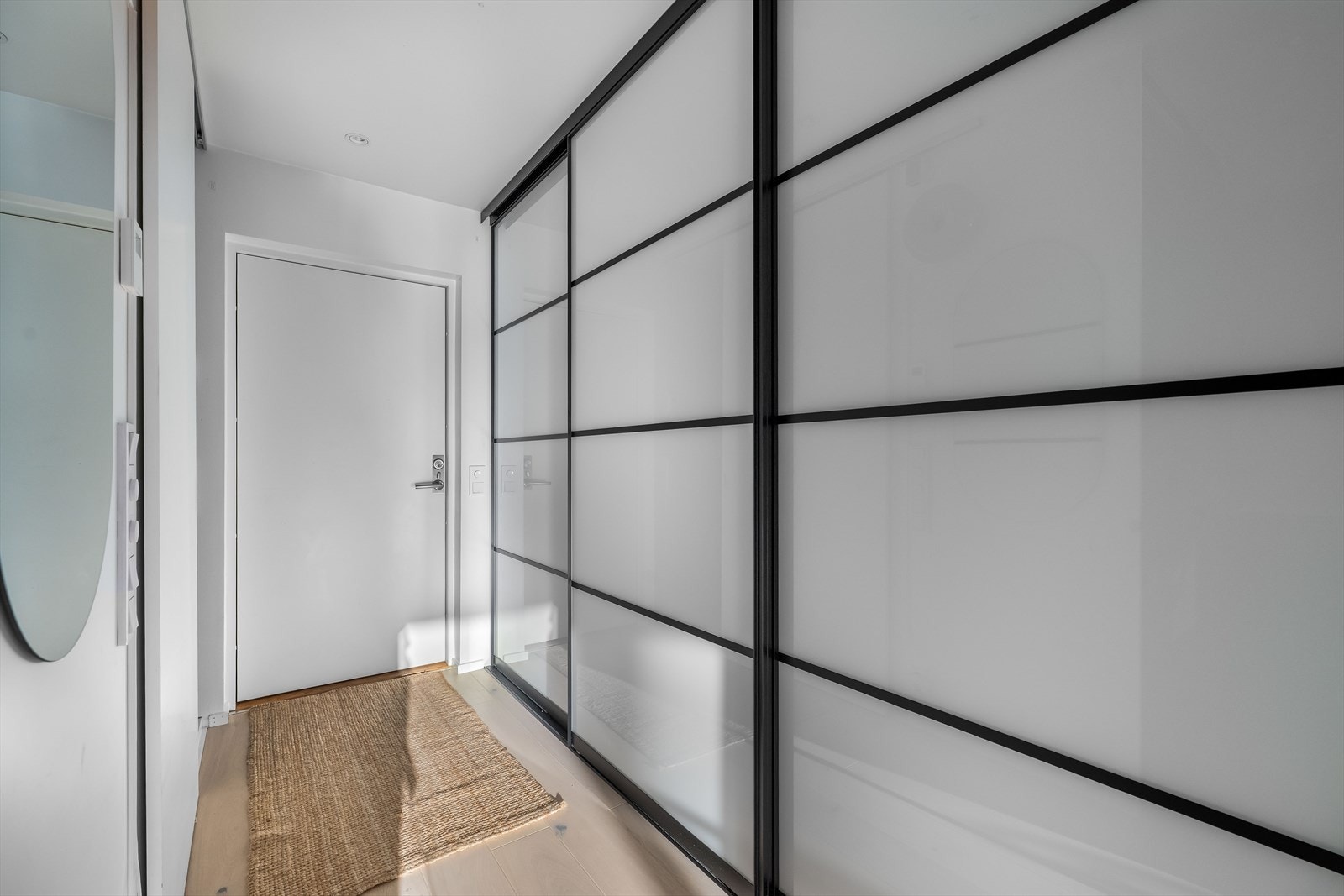 Boligen har en stilren, hvit ytterdør som skaper en lys og innbydende atmosfære i entréen, komplettert med downlights i himlingen for et moderne uttrykk Galleribilde