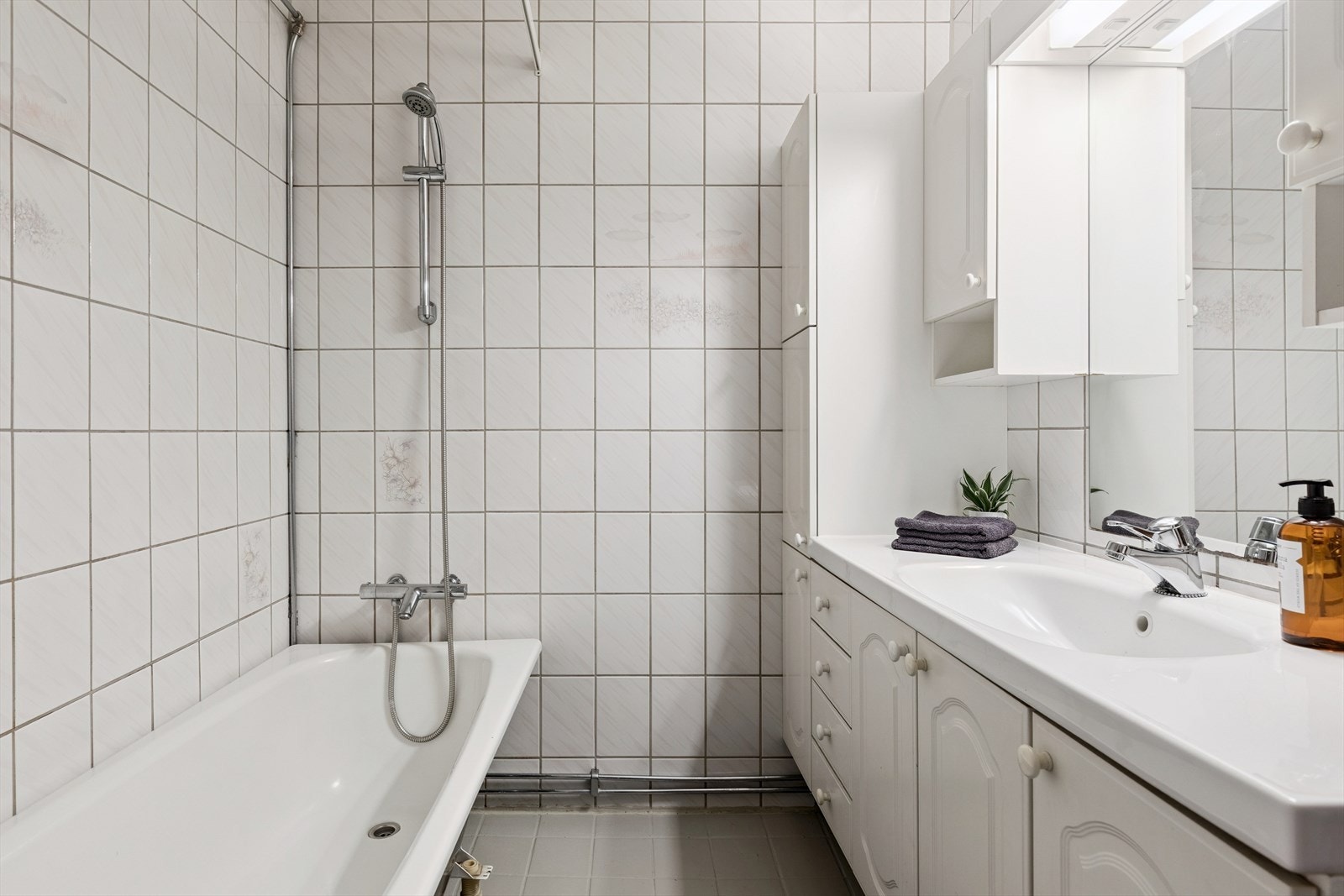 Flislagt bad i underetasje med gulvvarme, badekar med veggdusj og heldekkende servant i innredning. Galleribilde