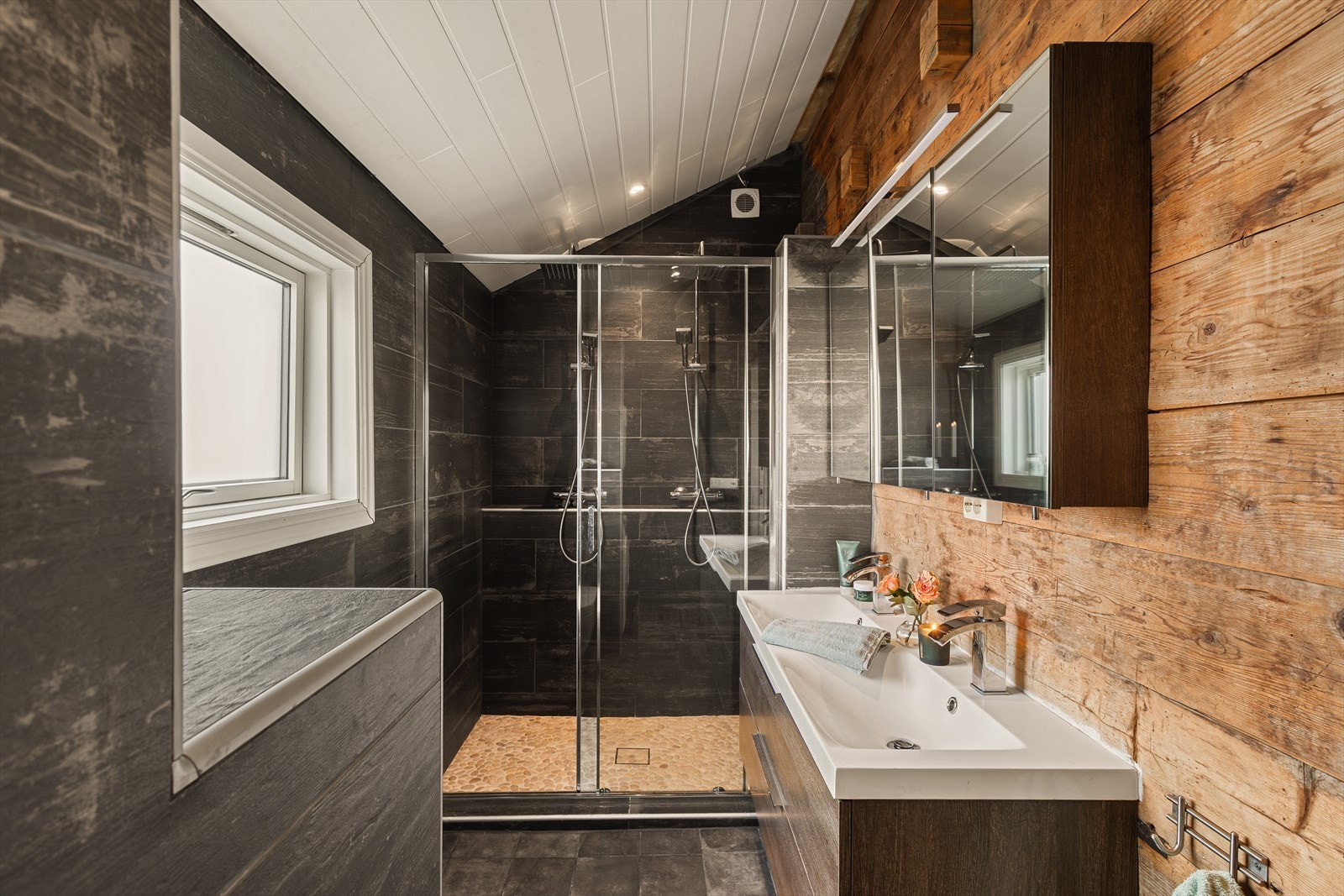 Badet i 1. etasje er praktisk innredet, og inneholder servant med møblement og speilskap, dobbel servant, vegghengt toalett og dusjhjørne med to dusjer Galleribilde