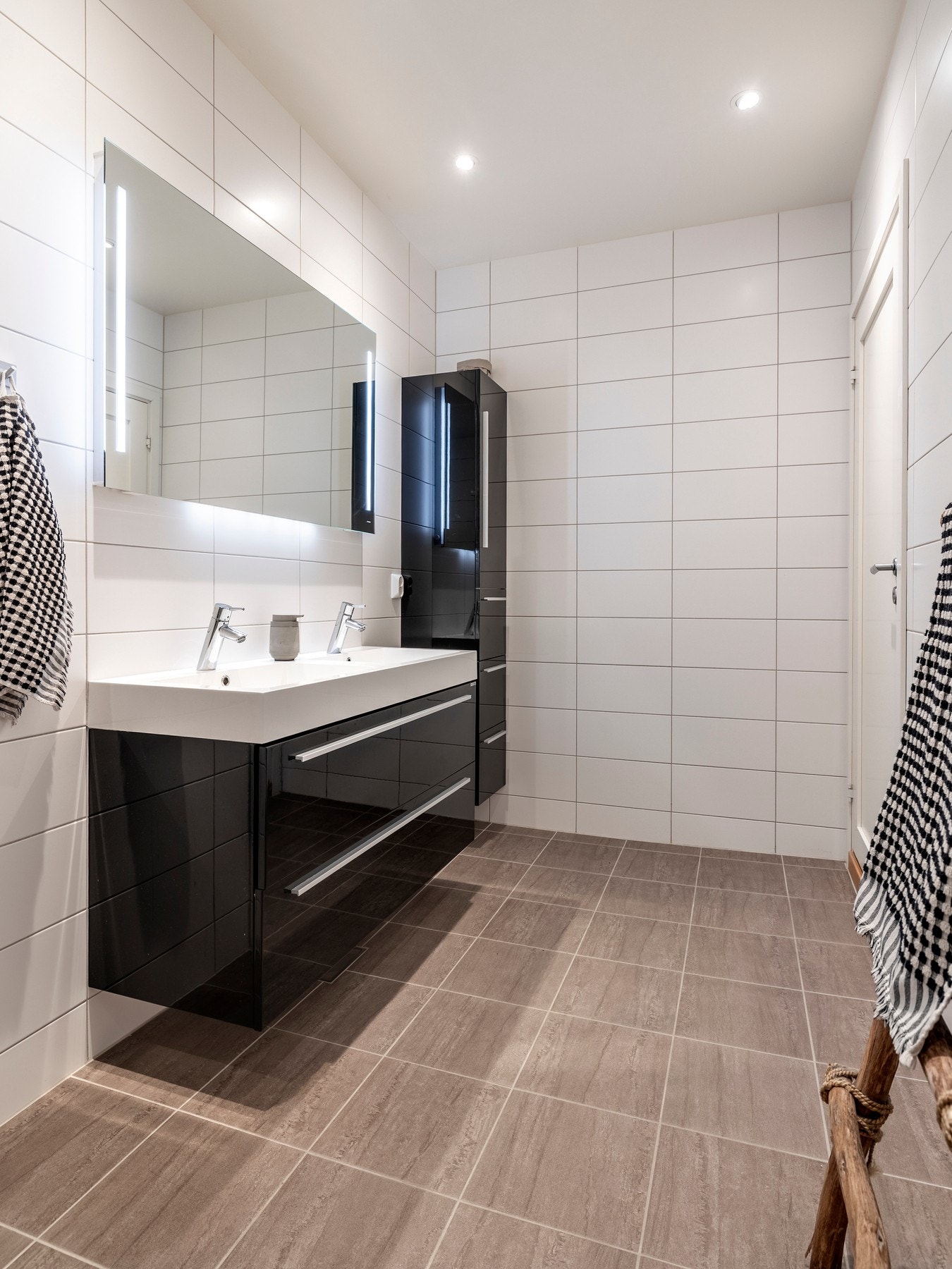 Badet er innredet med dobbel servant, speil med lys på vegg over servant, vegghengt toalett, skjermet dusjhjørne og ett høyskap på vegg for ekstra oppbevaring. Galleribilde