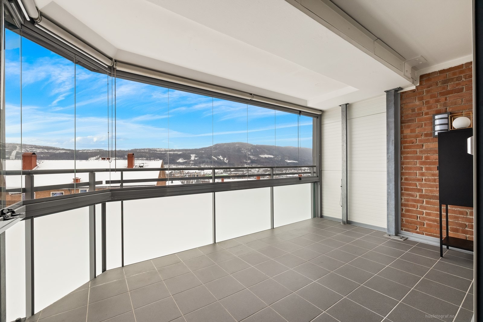 Sørvendt innglasset balkong på ca. 10 kvm. med innvendige rullgardiner og flislagt gulv. Galleribilde