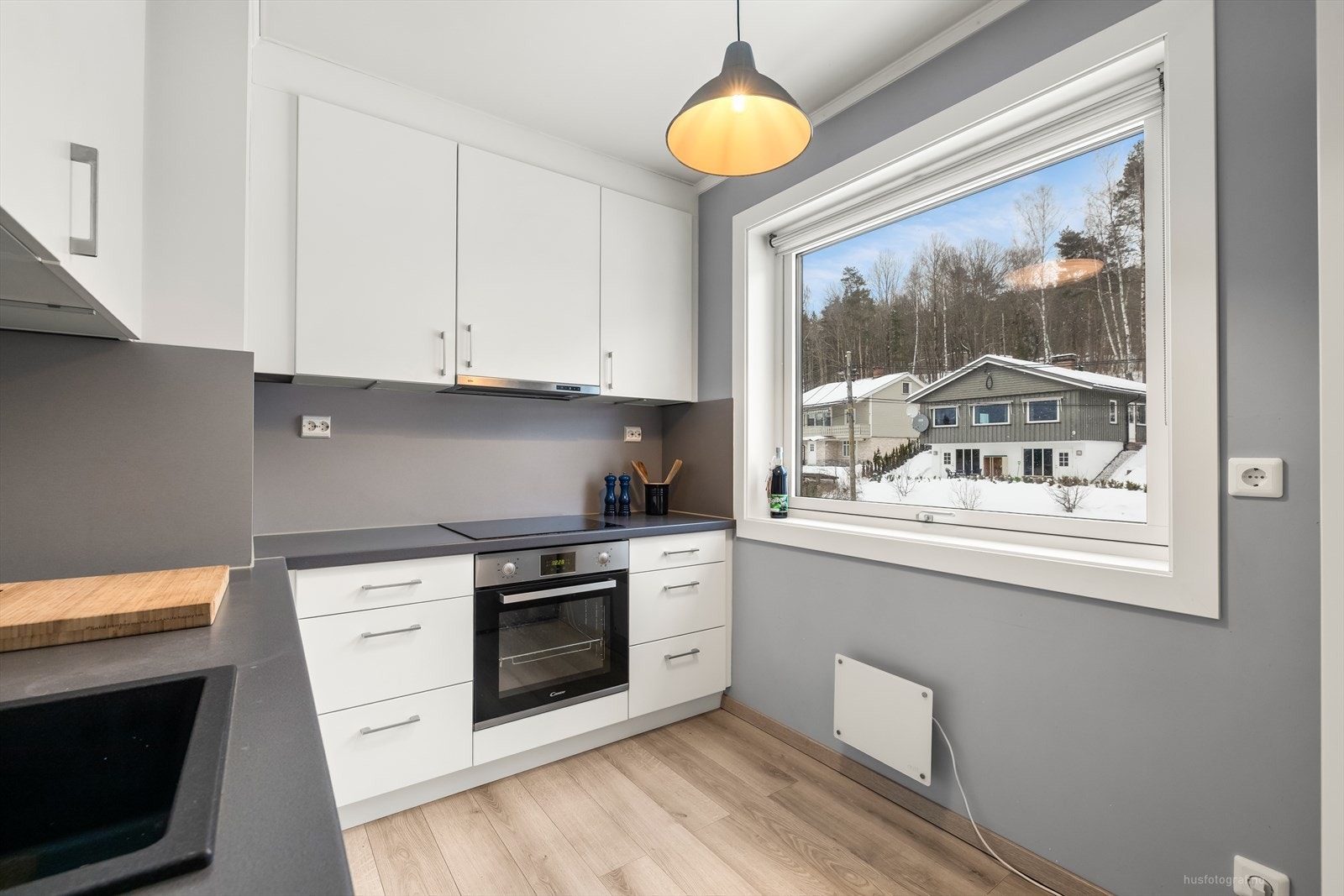 Pent kjøkken (fra ca. 2017) med hvit glatt kjøkkeninnredning. Integrerte hvitevarer med keramisk koketopp, stekeovn og oppvaskmaskin. Galleribilde