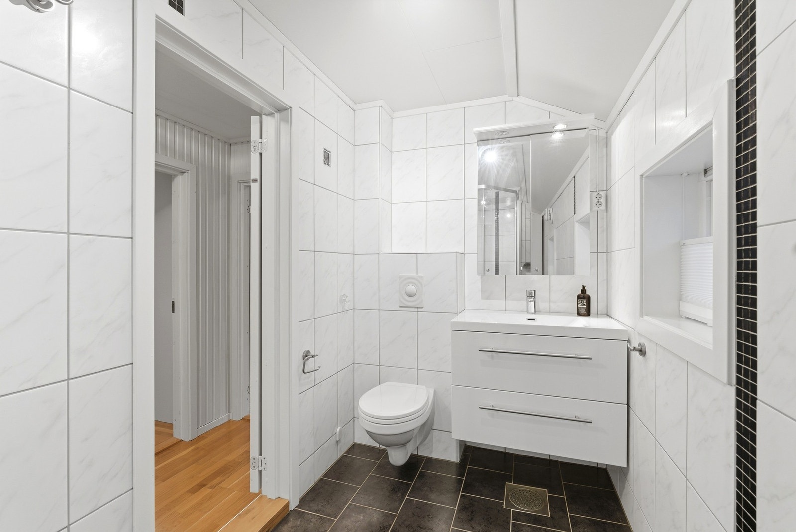 Flislagt bad fra 2010, i klassisk og tidløs utforming. Innredning med nedfelt servant, veggmontert toalett og dusjkabinett. Galleribilde