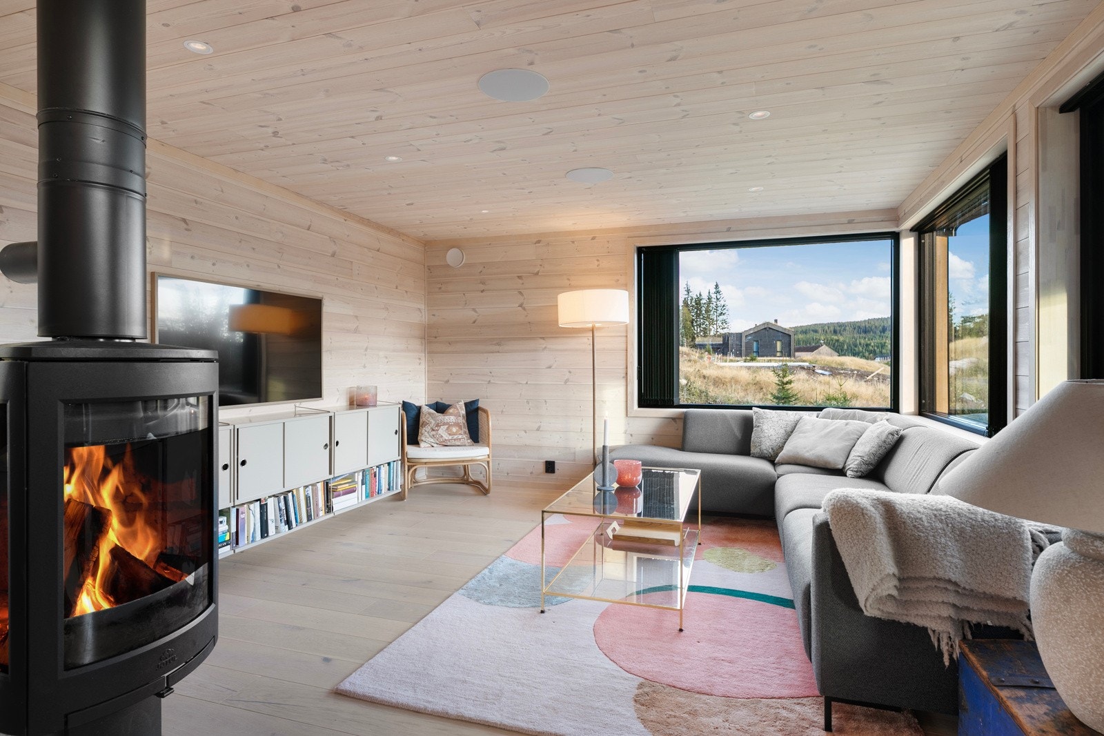 Midt i rommet er det en flott peisovn med glassdør som gir god varme og hygge. Galleribilde