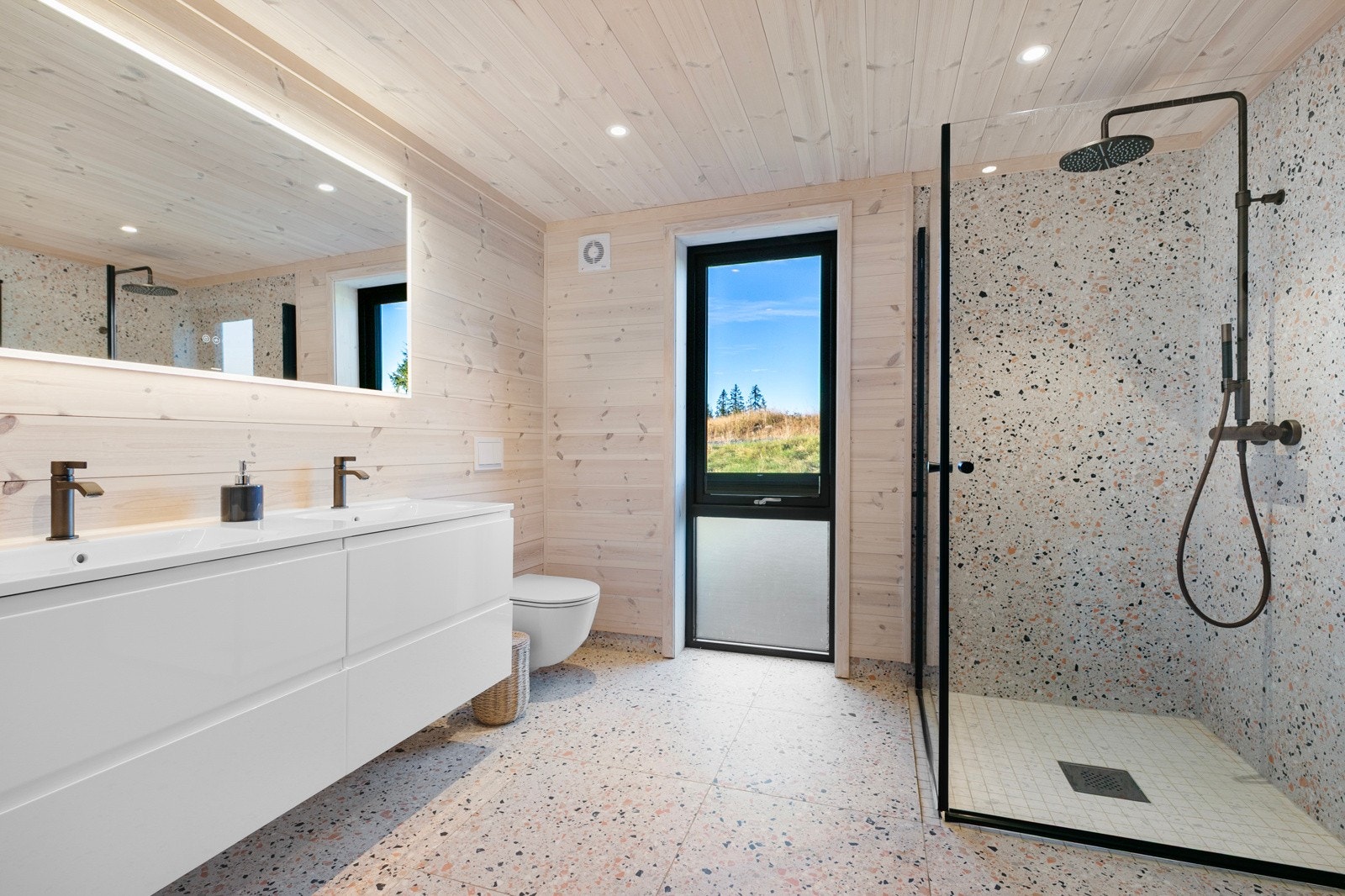 Bad ved gang med flislagt gulv med gulvvarme og panel og fliser på vegger. Galleribilde