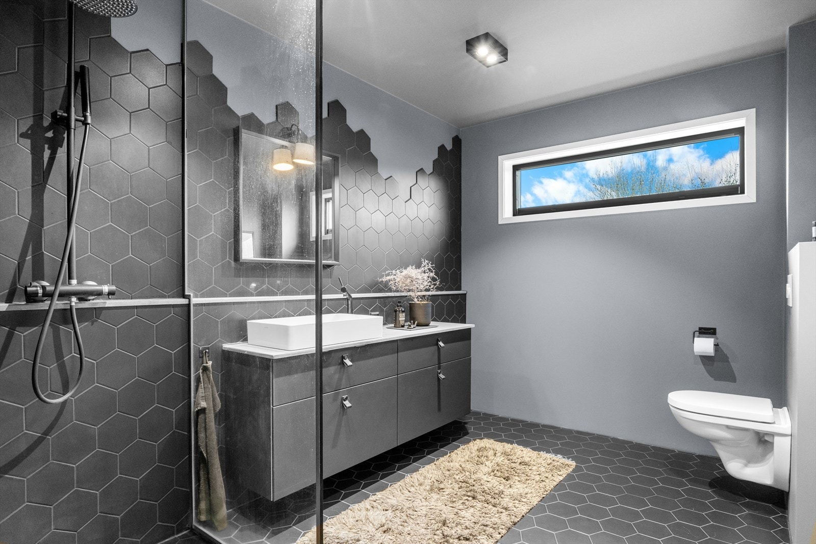 Bad i 1. etasje med kule detaljer, dusjnisje, vegghengt seksjon med servant samt vegghengt toalett. Galleribilde