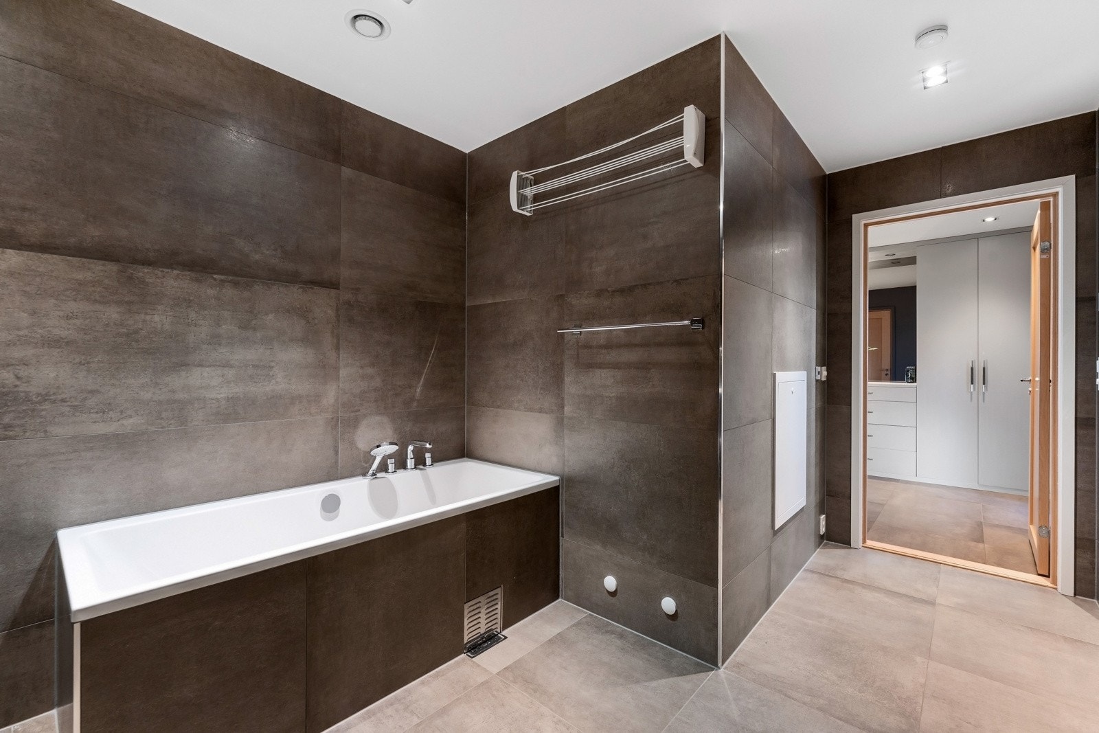 Her finnes opplegg for både vaskemaskin og tørketrommel under benkeplaten, i tillegg til et innmurt badekar med hånddusj. Galleribilde