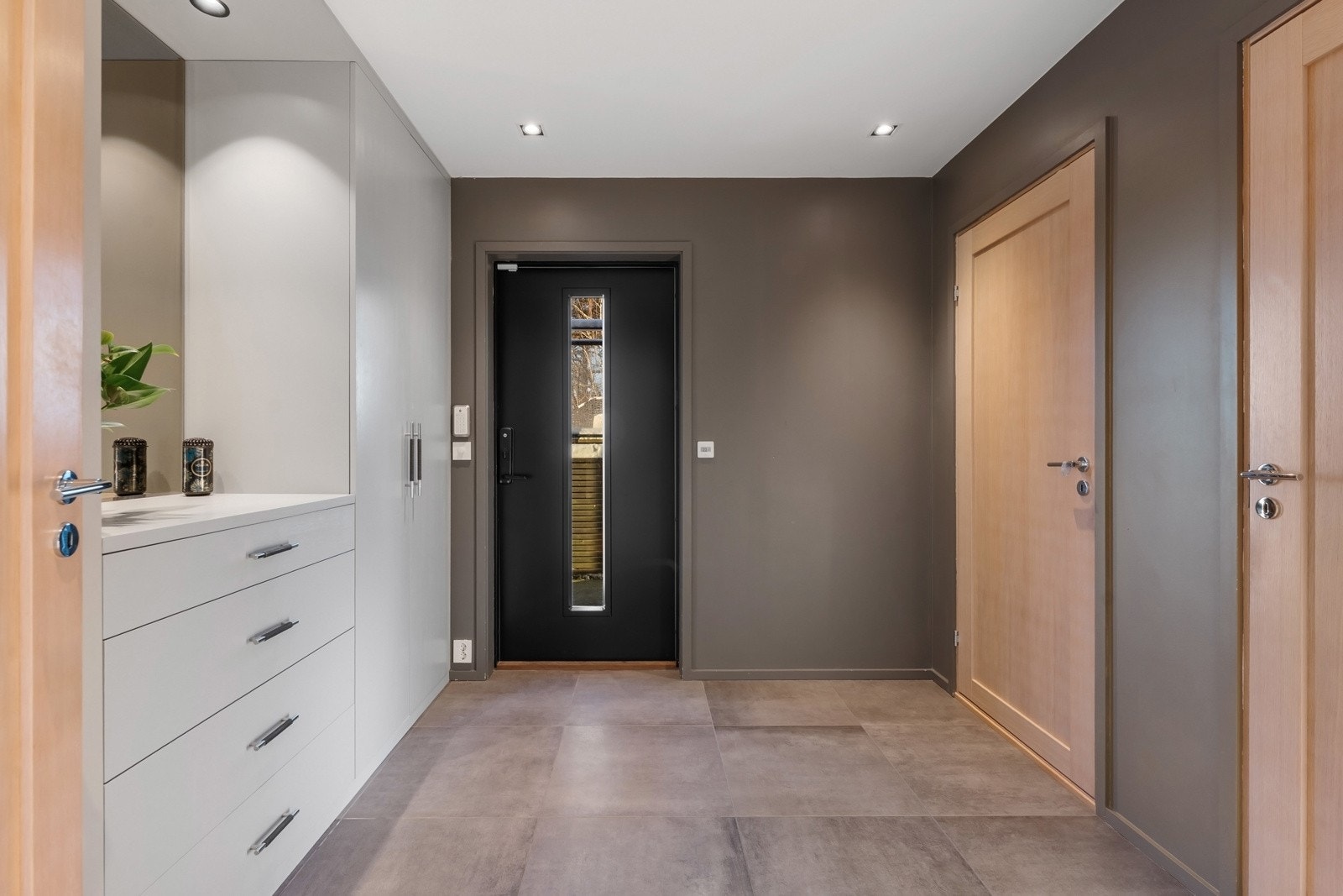 Romslig og innbydende entré, flislagt med vannbåren gulvvarme, som gir et godt førsteinntrykk og fungerer som boligens naturlige knutepunkt. Galleribilde