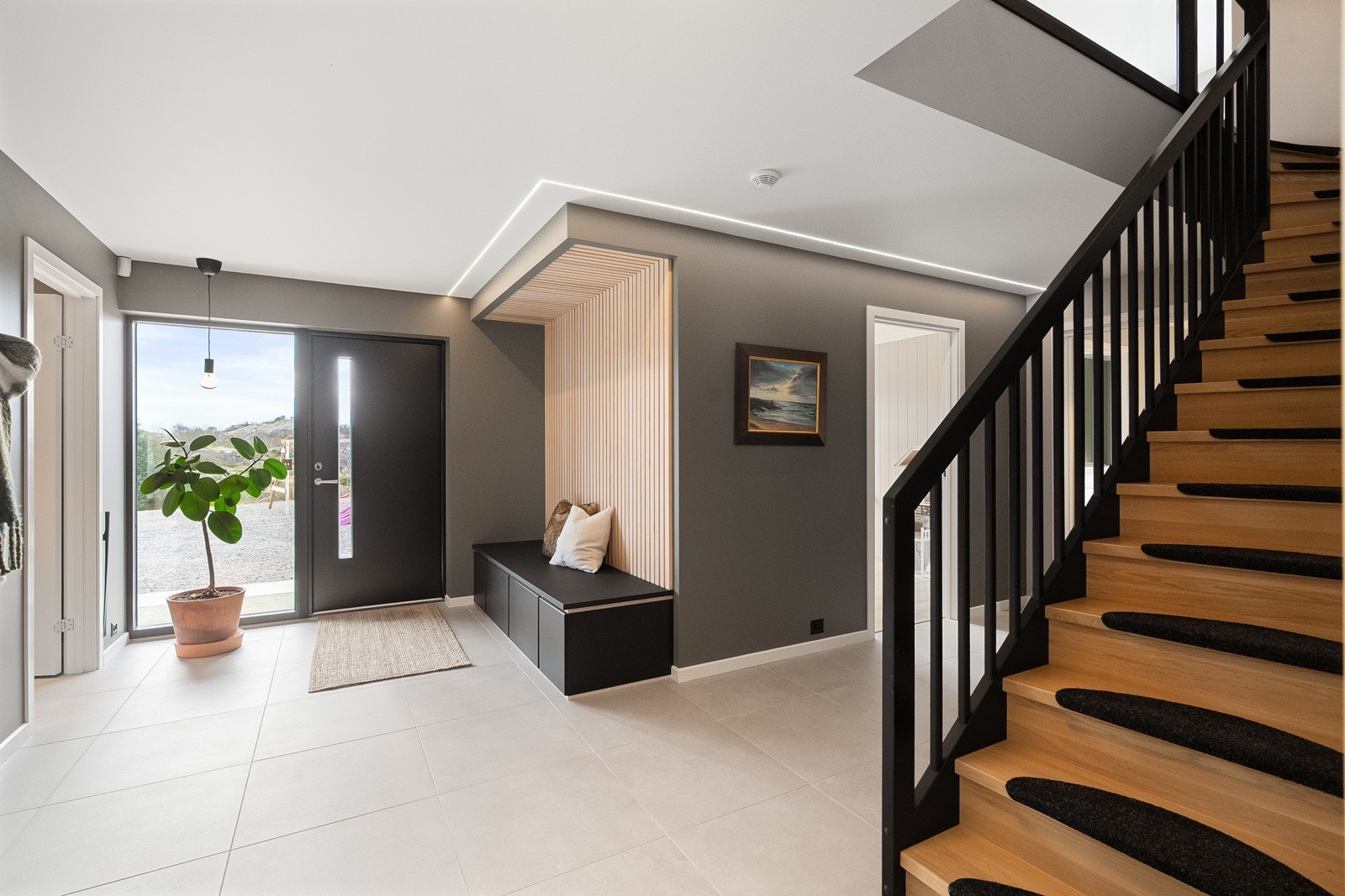 Entré/gang med store 60x60 fliser på gulv og ledstripe som belysning i tak. Galleribilde