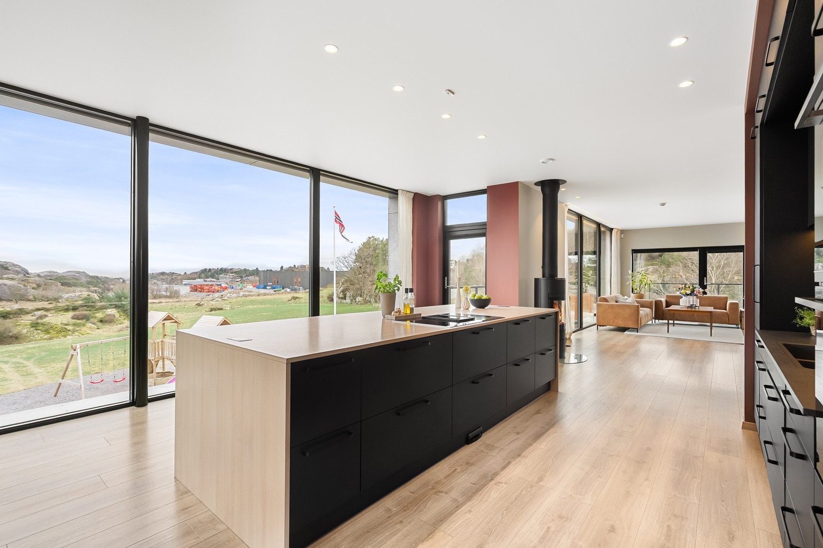 Moderne kjøkken med mørk utførelse. Stor kjøkkenøy som gir god benkeplass - feiebrett til sentralstøvsuger i sokkel og WallyFlex inne i et av skapene. Galleribilde